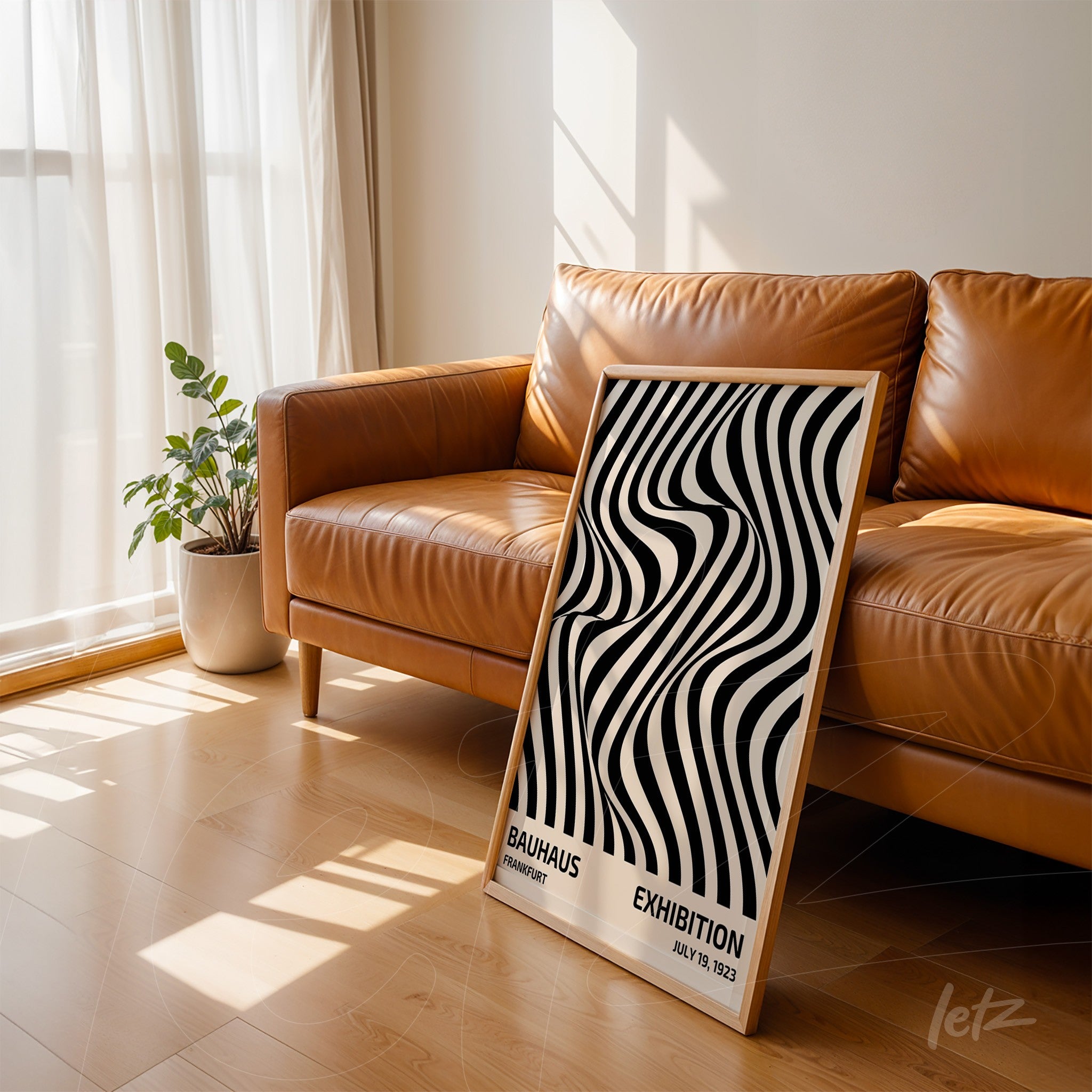 framed poster with black and white geometric pattern, resting against a brown leather sofa