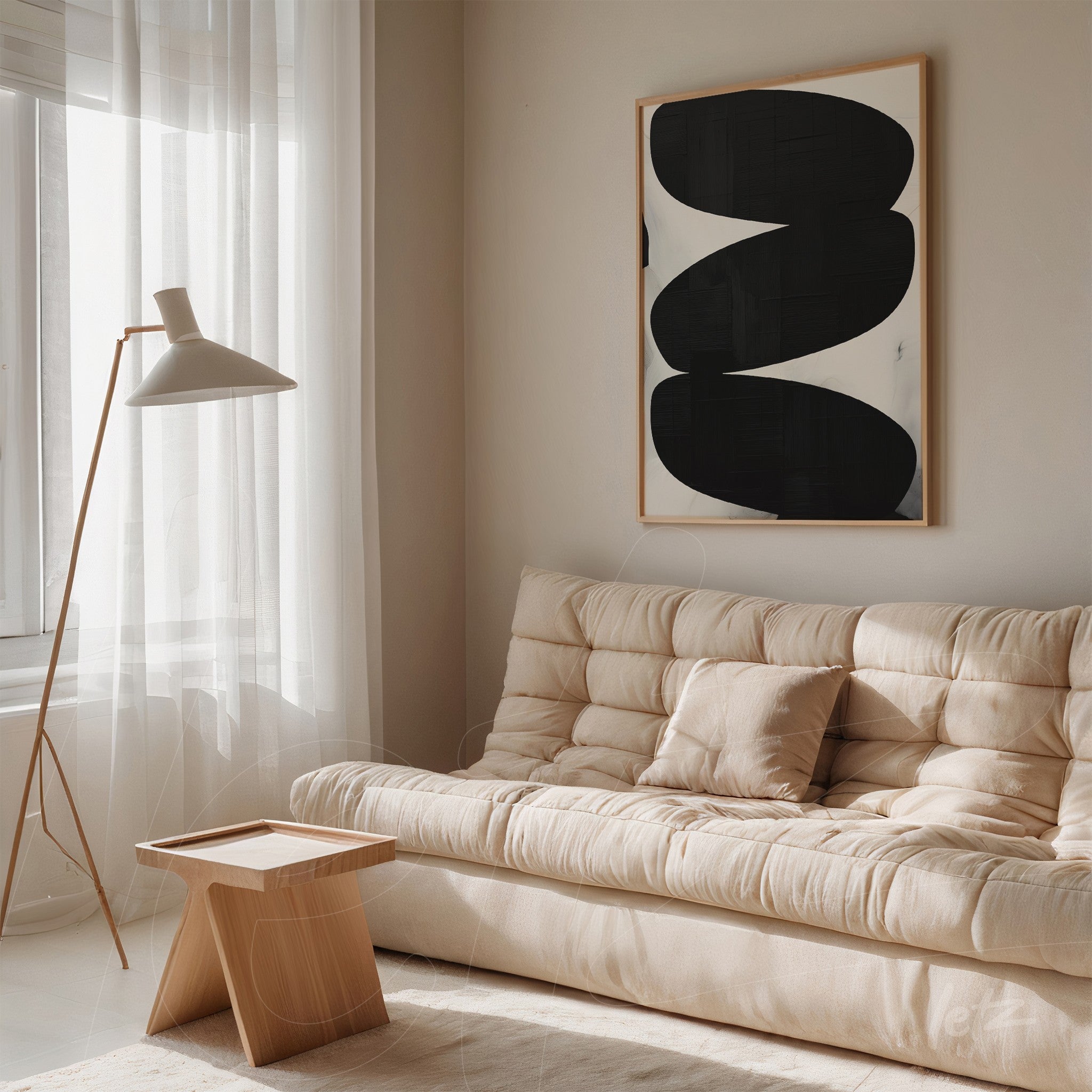 abstract wall art in black and white with light wood frame hanging on a light wall next to a beige sofa