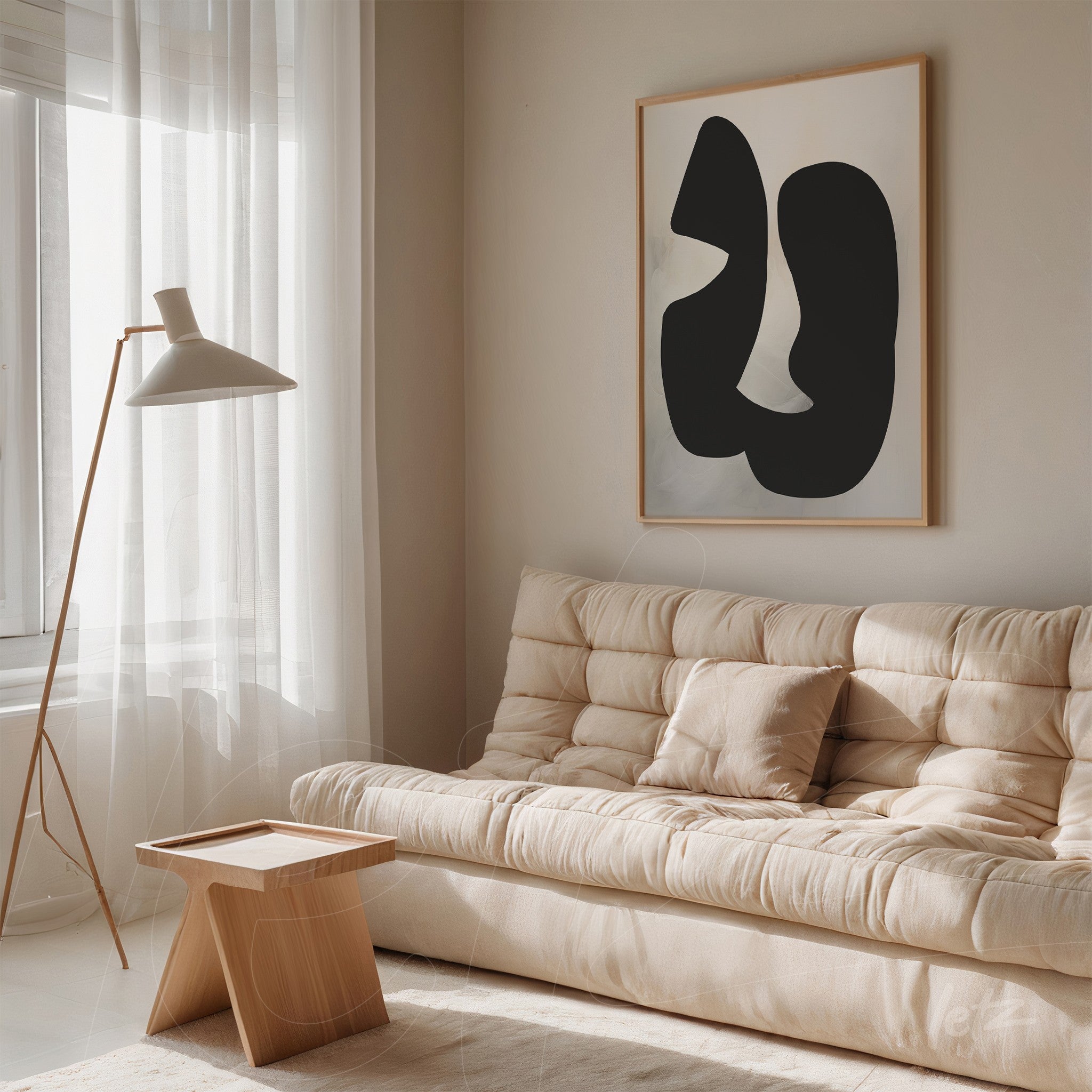 modern wall art featuring abstract black shapes in light frame against a neutral wall next to a beige sofa
