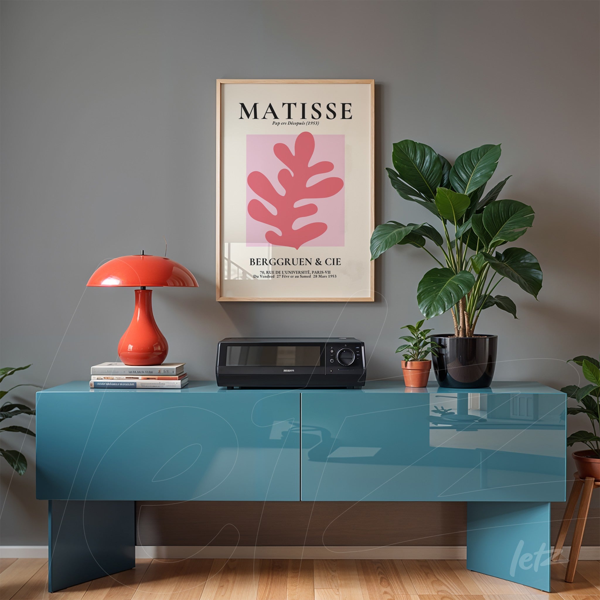 framed modern art print of pink leaf above blue cabinet in a room decorated with plants