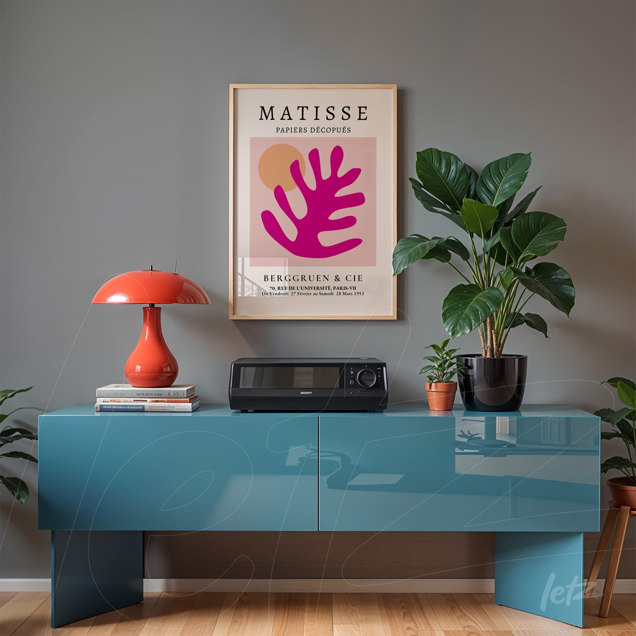 framed wall art featuring modern leaf design in pink background displayed on gray wall with blue furniture and indoor plants