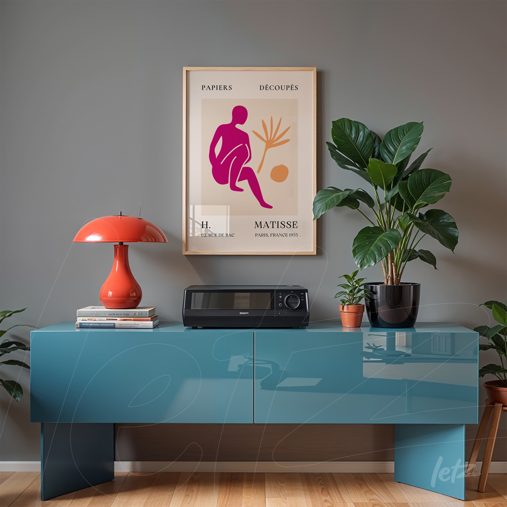 framed wall art featuring modern Matisse artwork on gray wall, displayed over blue furniture with decorative plants and a red lamp