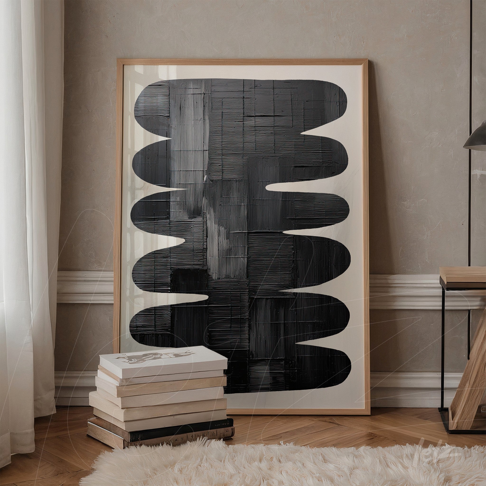 framed wall art featuring abstract black and white design displayed next to a stack of books on a wooden table