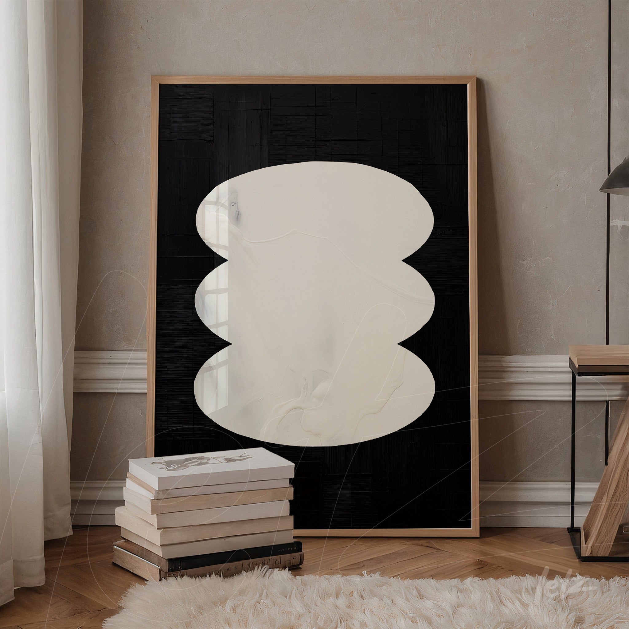modern artwork featuring abstract shape on black background, light frame displayed next to a stack of books in indoor setting