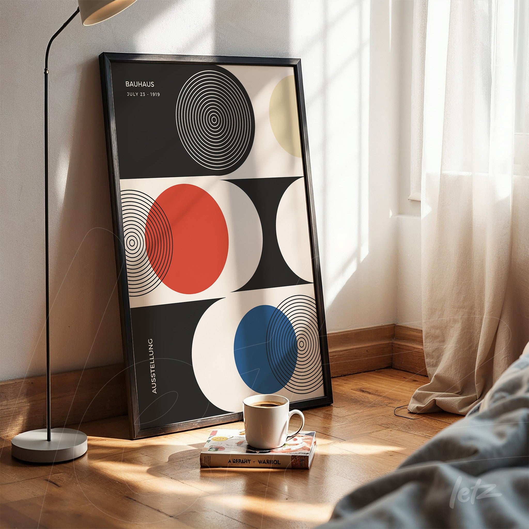 framed geometric bauhaus style art print propped on wooden floor, featuring colorful circles on black and white background, next to a modern lamp