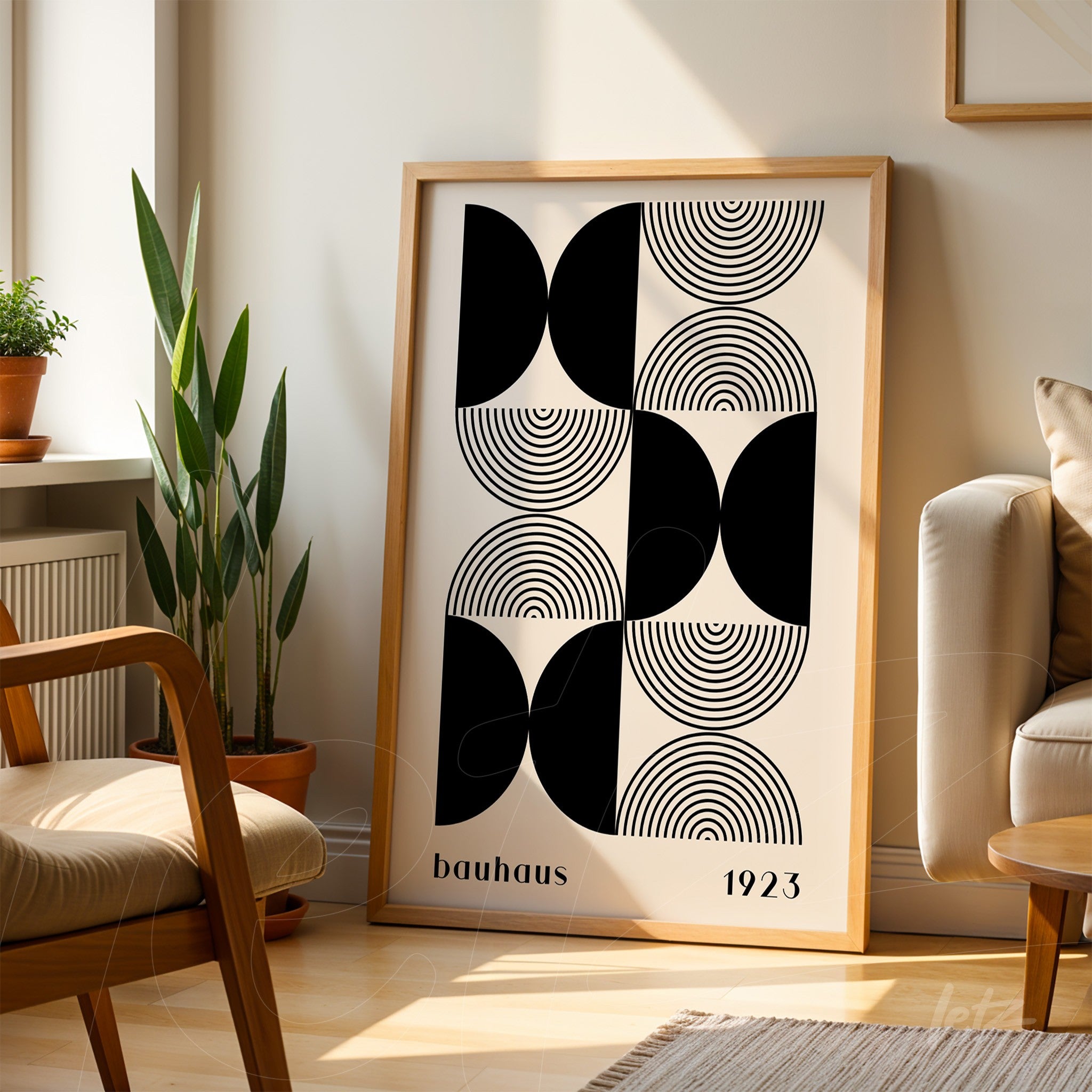 poster print featuring black and white geometric bauhaus-inspired art with light wood frame, resting on the floor beside a couch in a well-lit living room