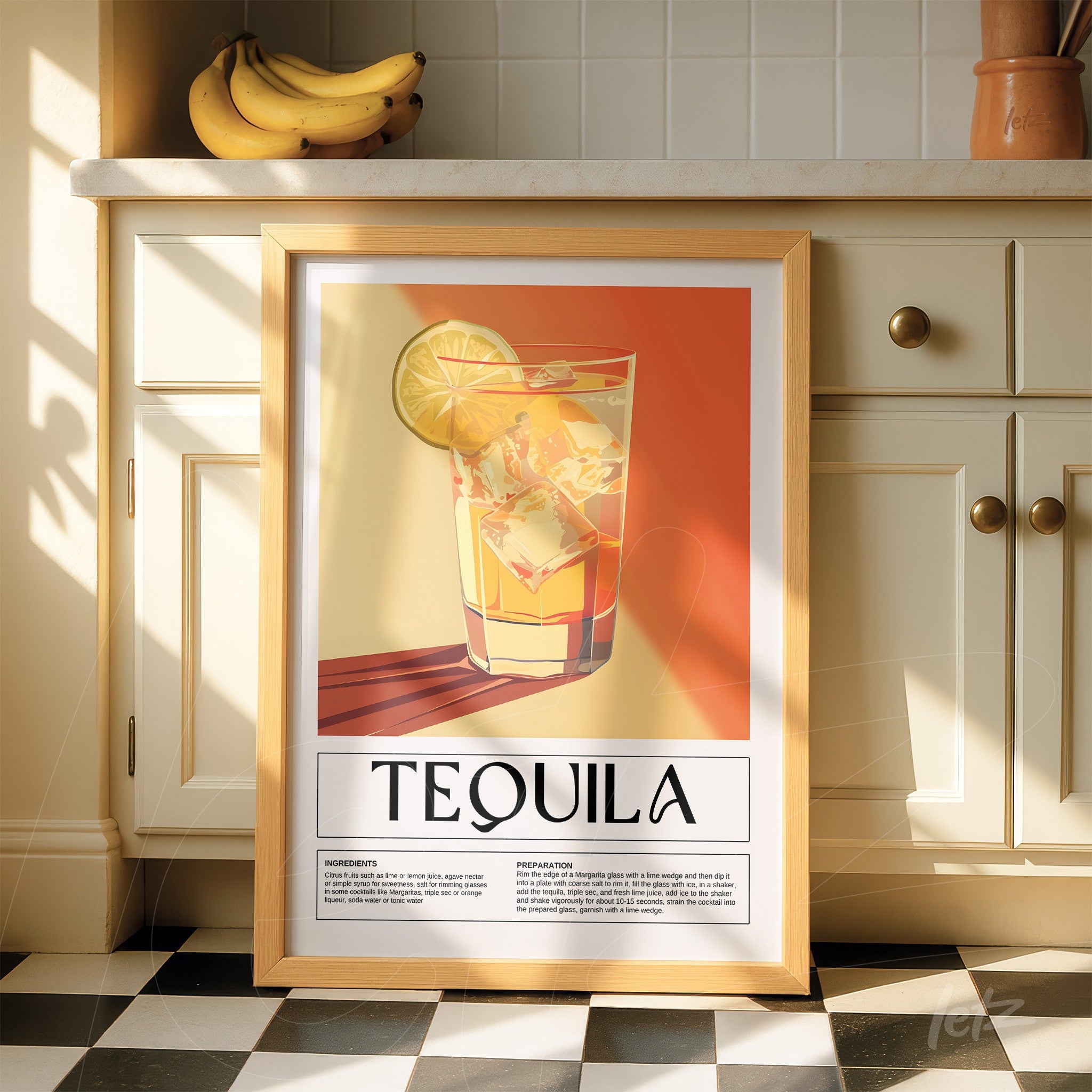 framed graphic art of tequila cocktail with light wood frame displayed on kitchen counter against a yellow and orange backdrop