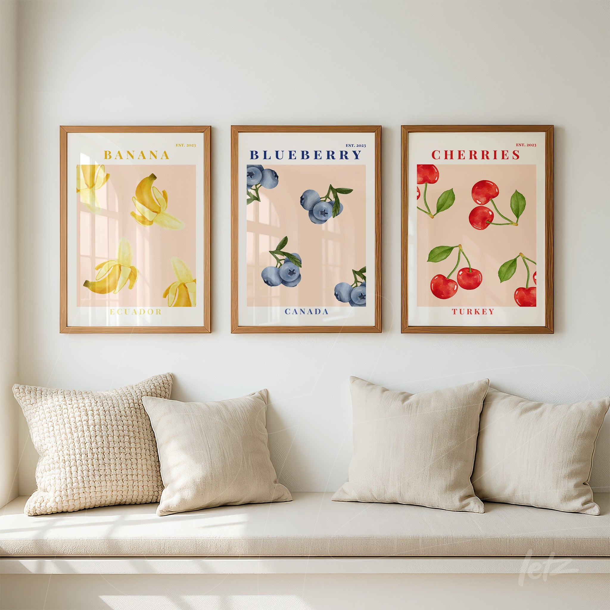 series of decorative framed artworks featuring illustrations of banana, blueberry, and cherry with light wood frames displayed on a light wall