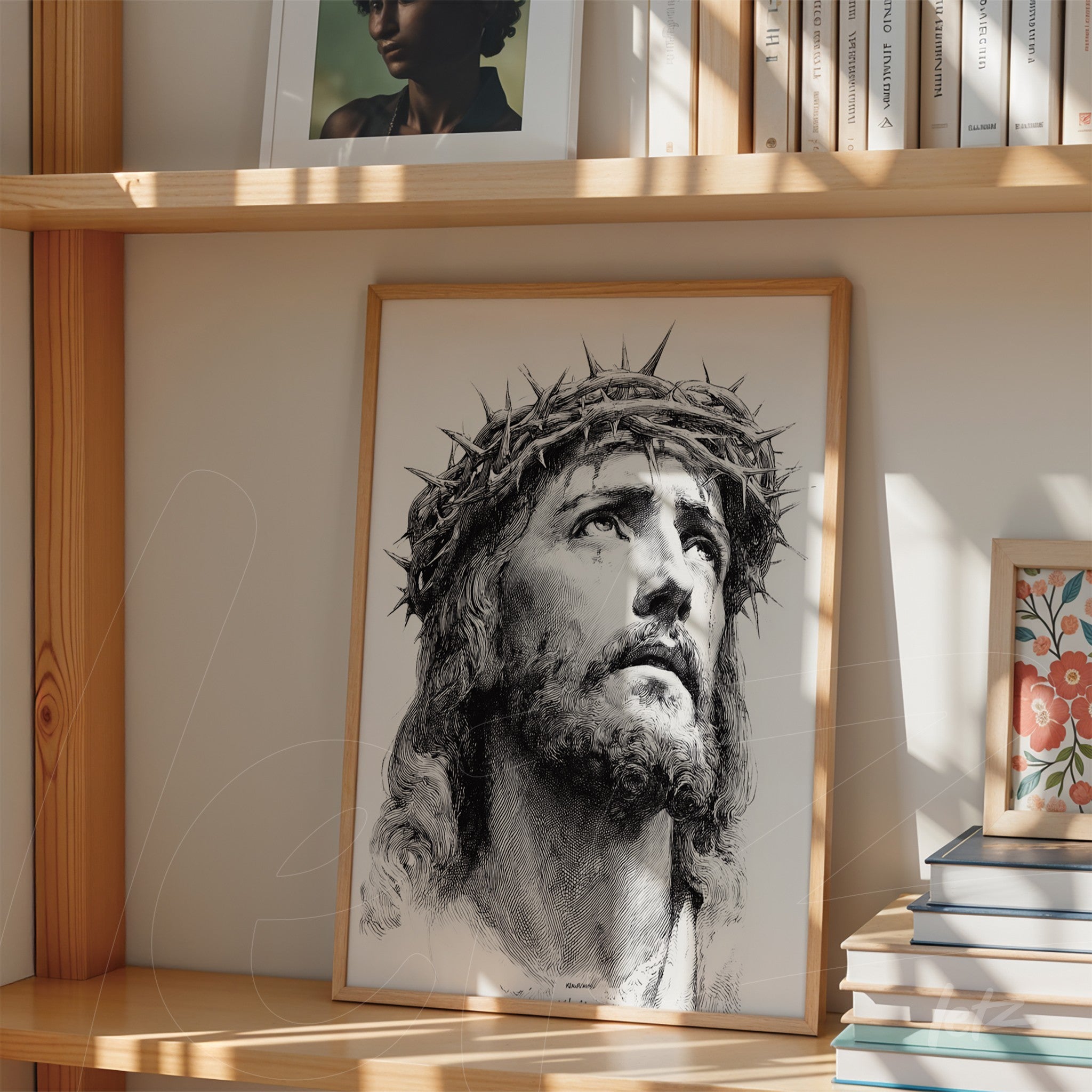 framed artwork featuring a detailed portrait of Jesus Christ with a crown of thorns displayed on a shelf beside books