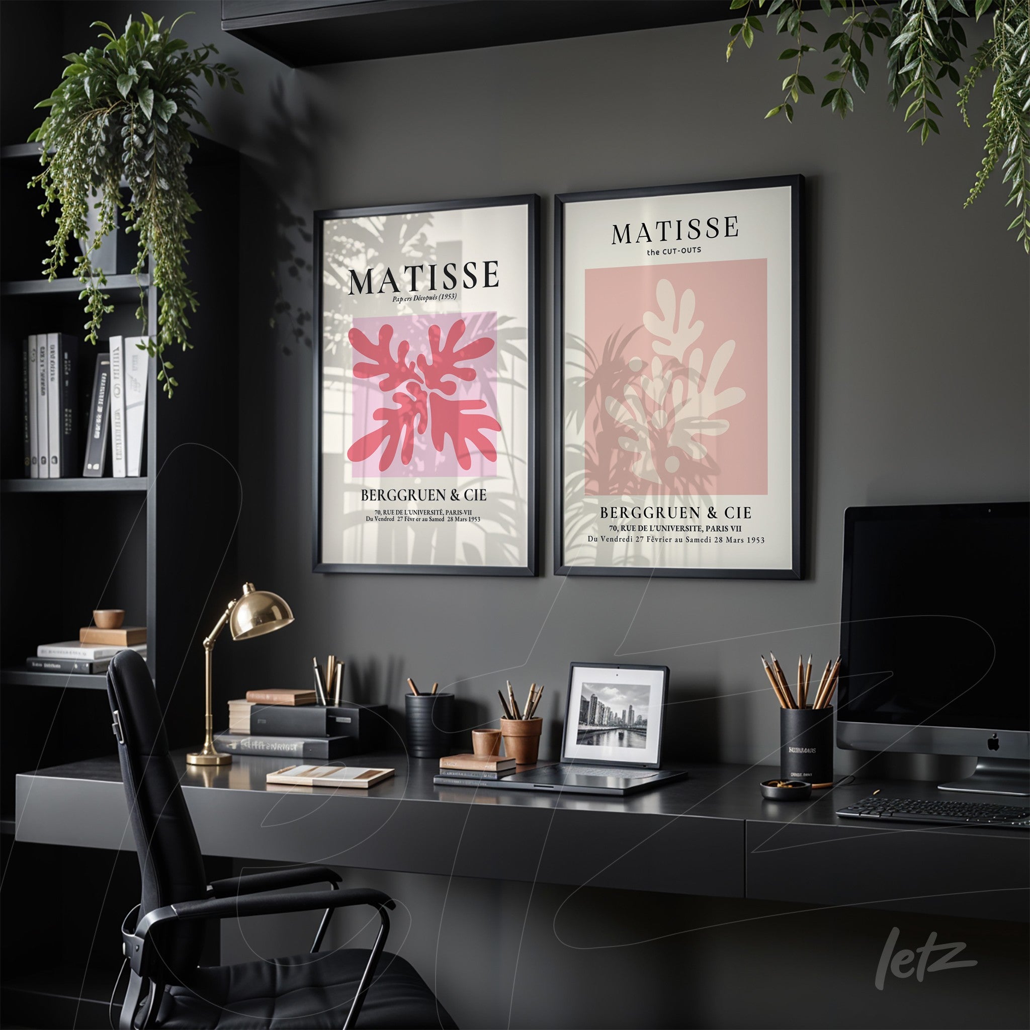 a composition of two framed wall art pieces displayed on a black desk, featuring designs inspired by Matisse, one with a pink leaf and the other with red background highlighting foliage