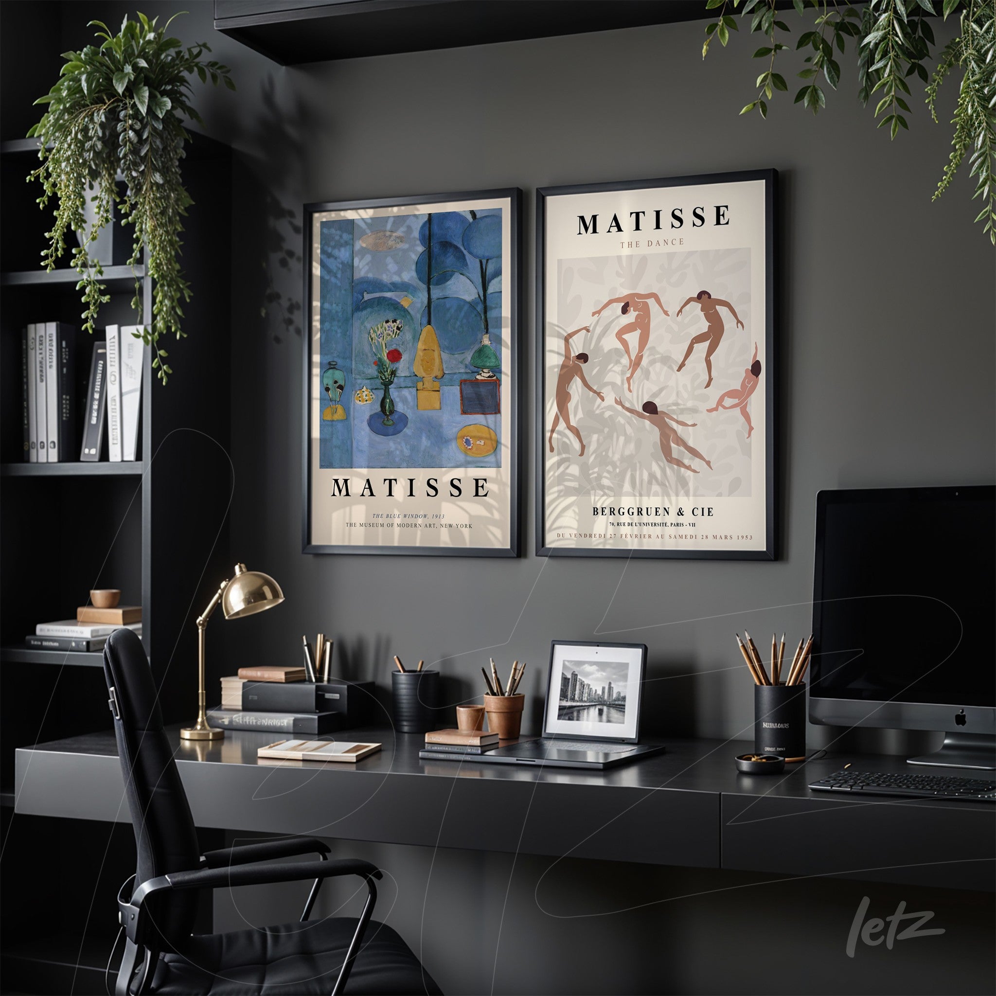 composition with two black framed wall art pieces displayed over a dark desk, featuring a dance scene and a landscape in blue tones