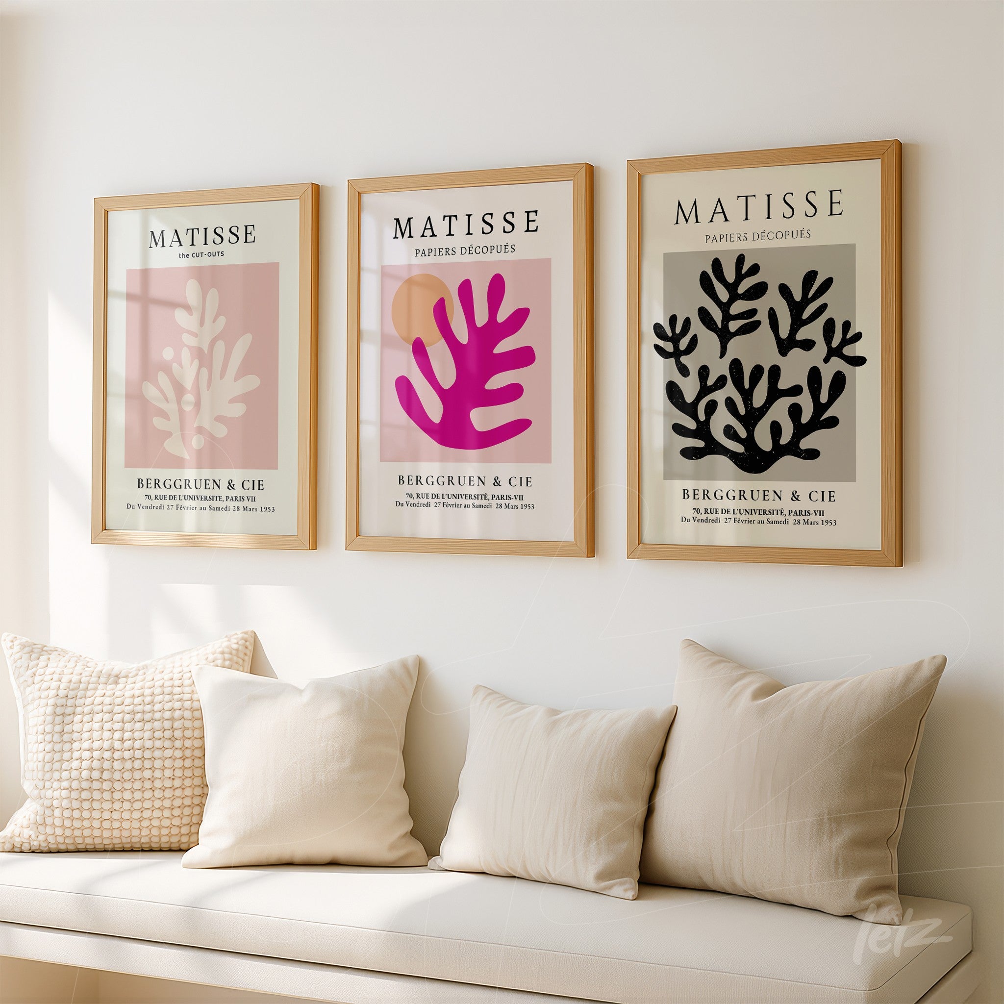 composition of three modern wall art pieces with light wood frames showcasing botanical designs in pink and black