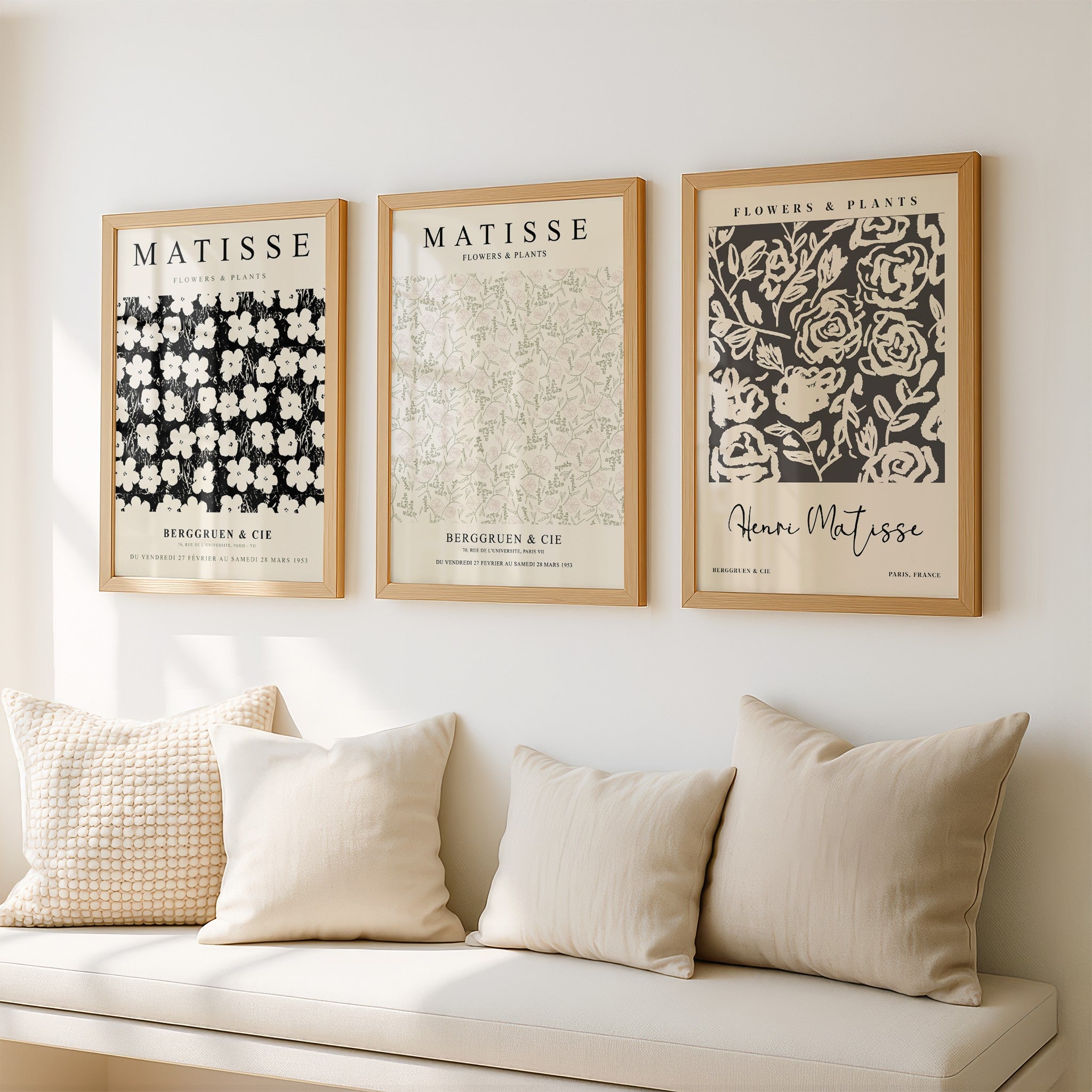 set of three framed artworks featuring floral and plant patterns on a light wall, displayed in light wooden frames