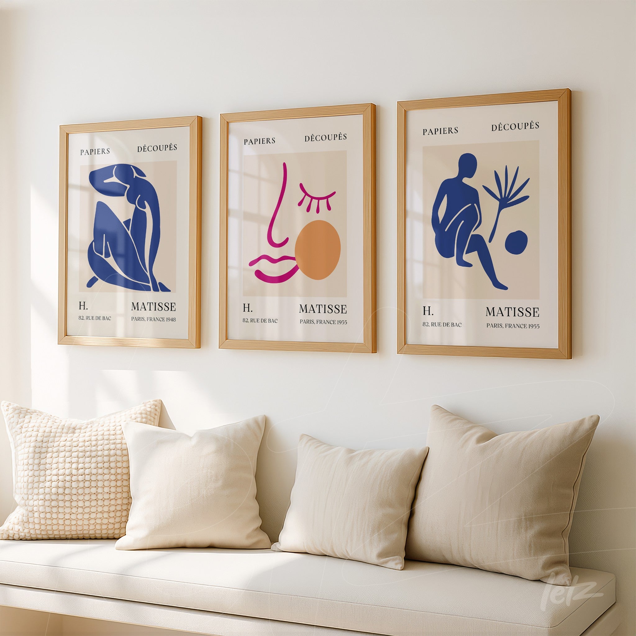 composition of three framed modern art pieces in light wood, showcasing abstract shapes in shades of blue, pink, and ochre against a neutral background