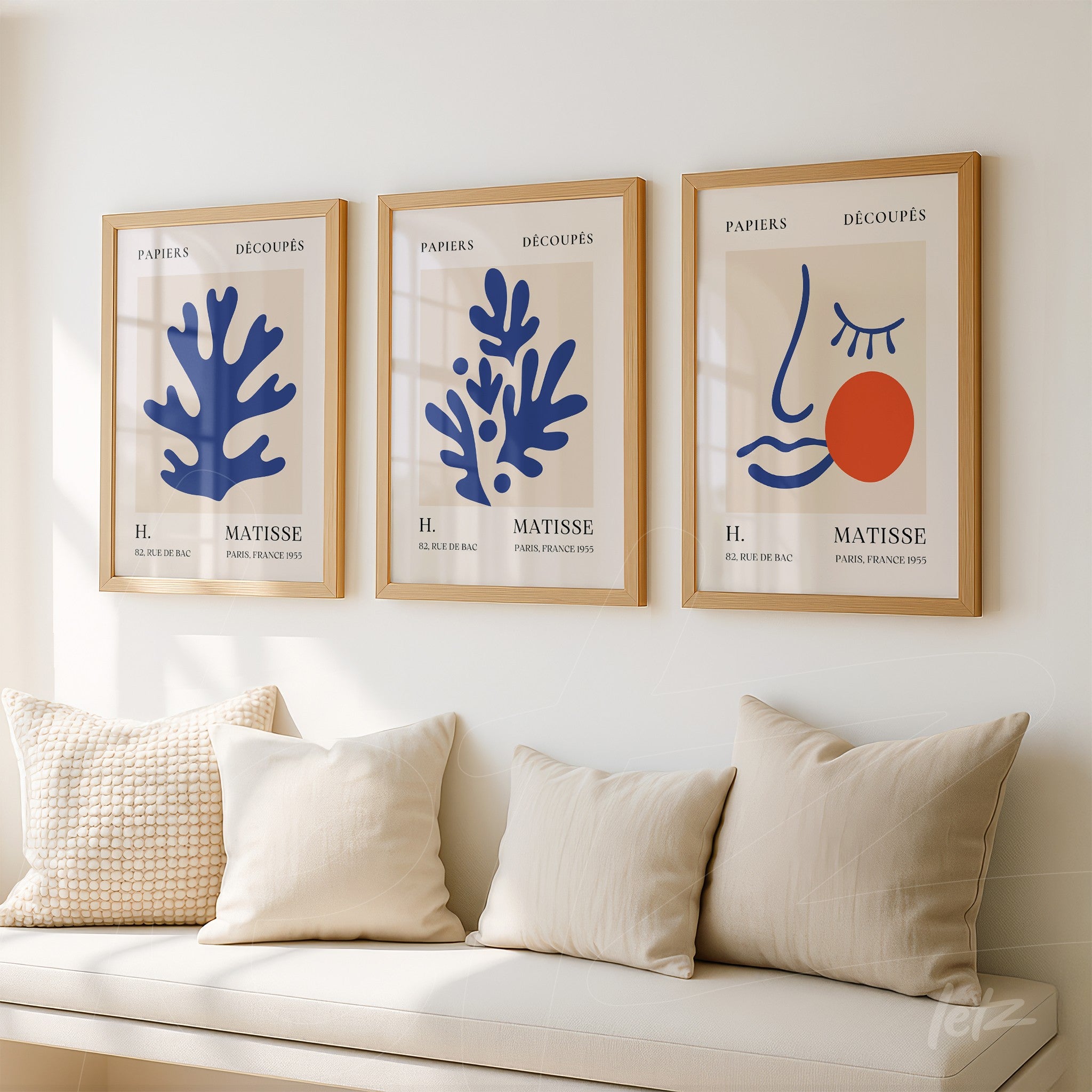collection of framed modern art featuring abstract plant shapes and faces in light wood frames on a neutral wall
