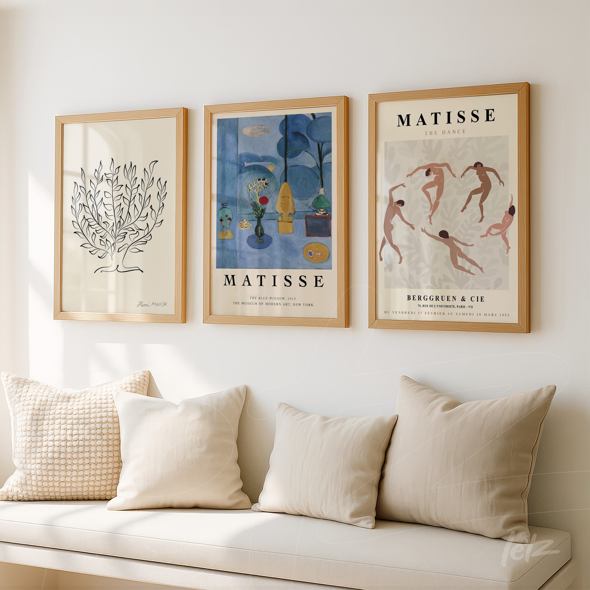 composition of three decorative wall art frames in light wood displayed on a white wall, featuring an abstract tree artwork, a blue painting by Matisse, and a circular dance illustration