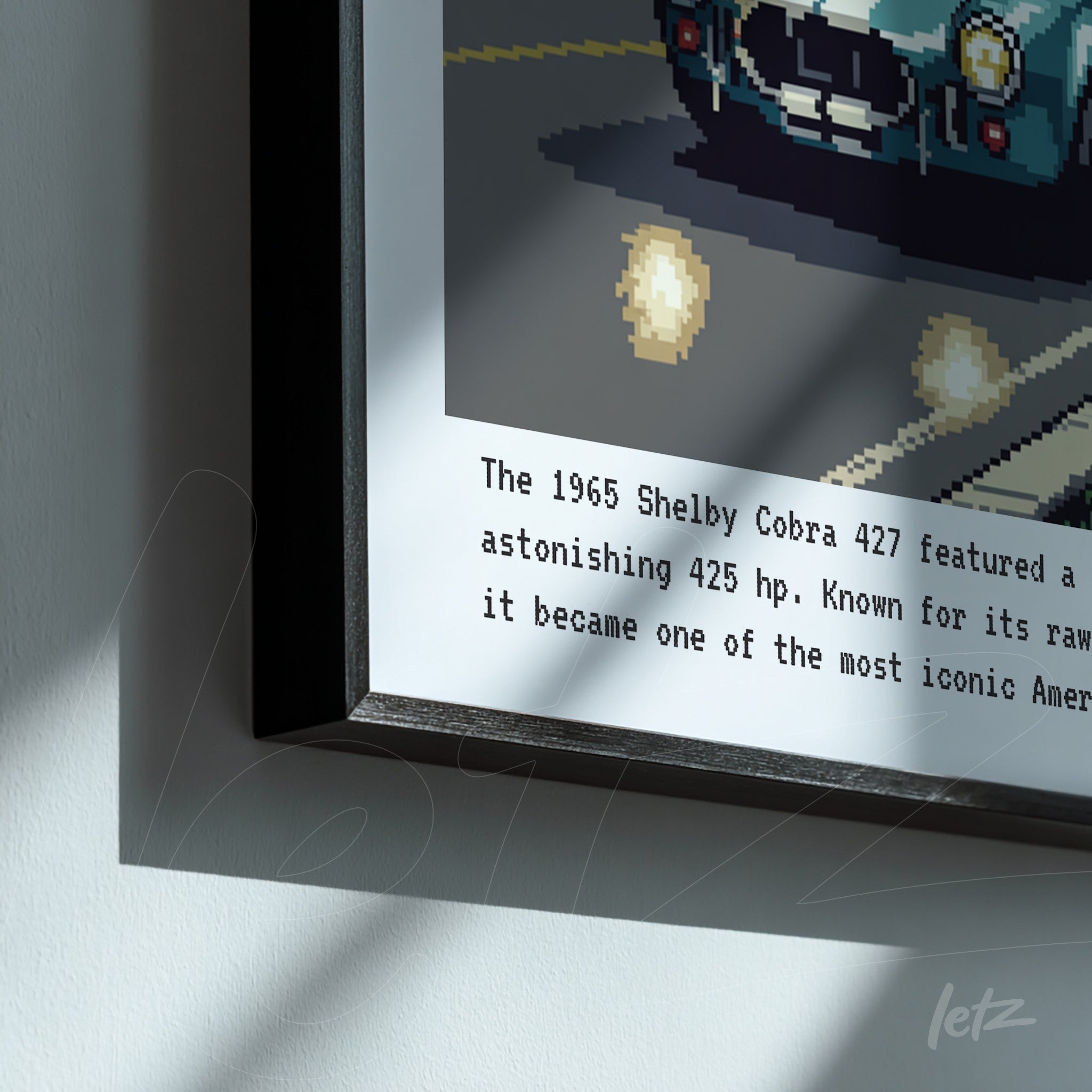 framed pixel art of the 1965 Shelby Cobra 427 with black frame, featuring descriptive text on light gray background
