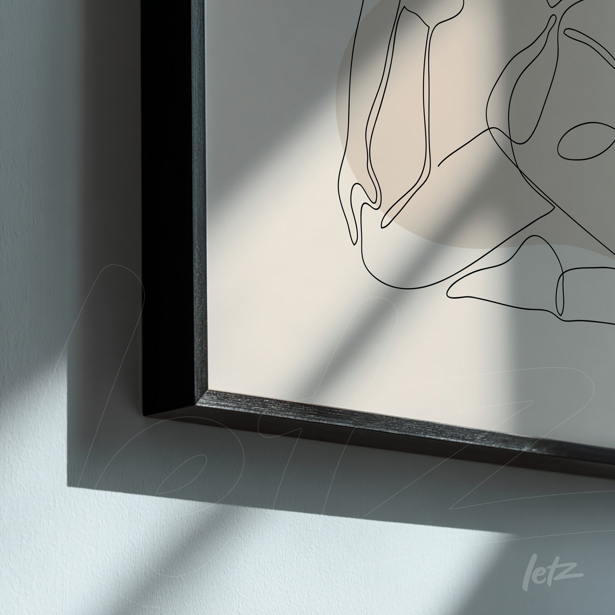 detail of framed minimalist line art with black lines on beige background and black frame displayed on white wall