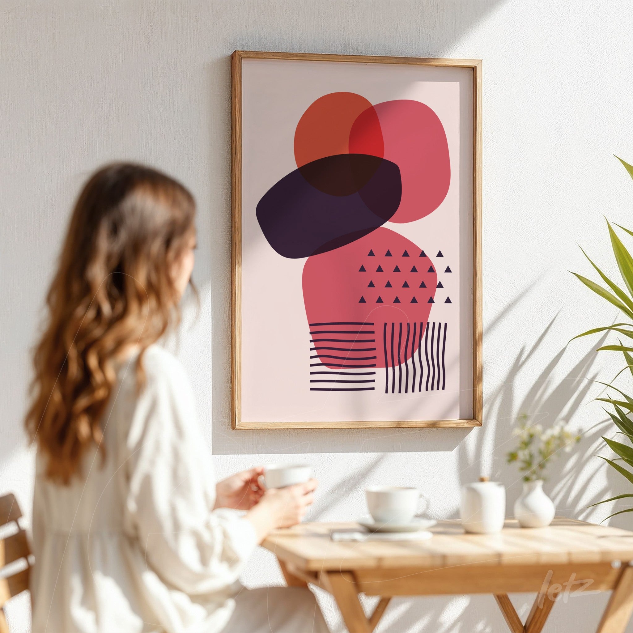 abstract art with geometric shapes in pink and purple framed in light wood displayed on white wall