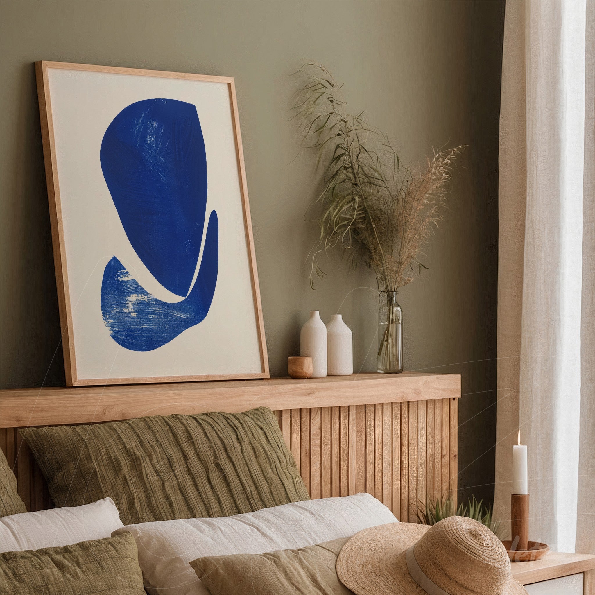 abstract wall art in blue framed with light wood displayed above a wooden headboard in a room with olive green walls
