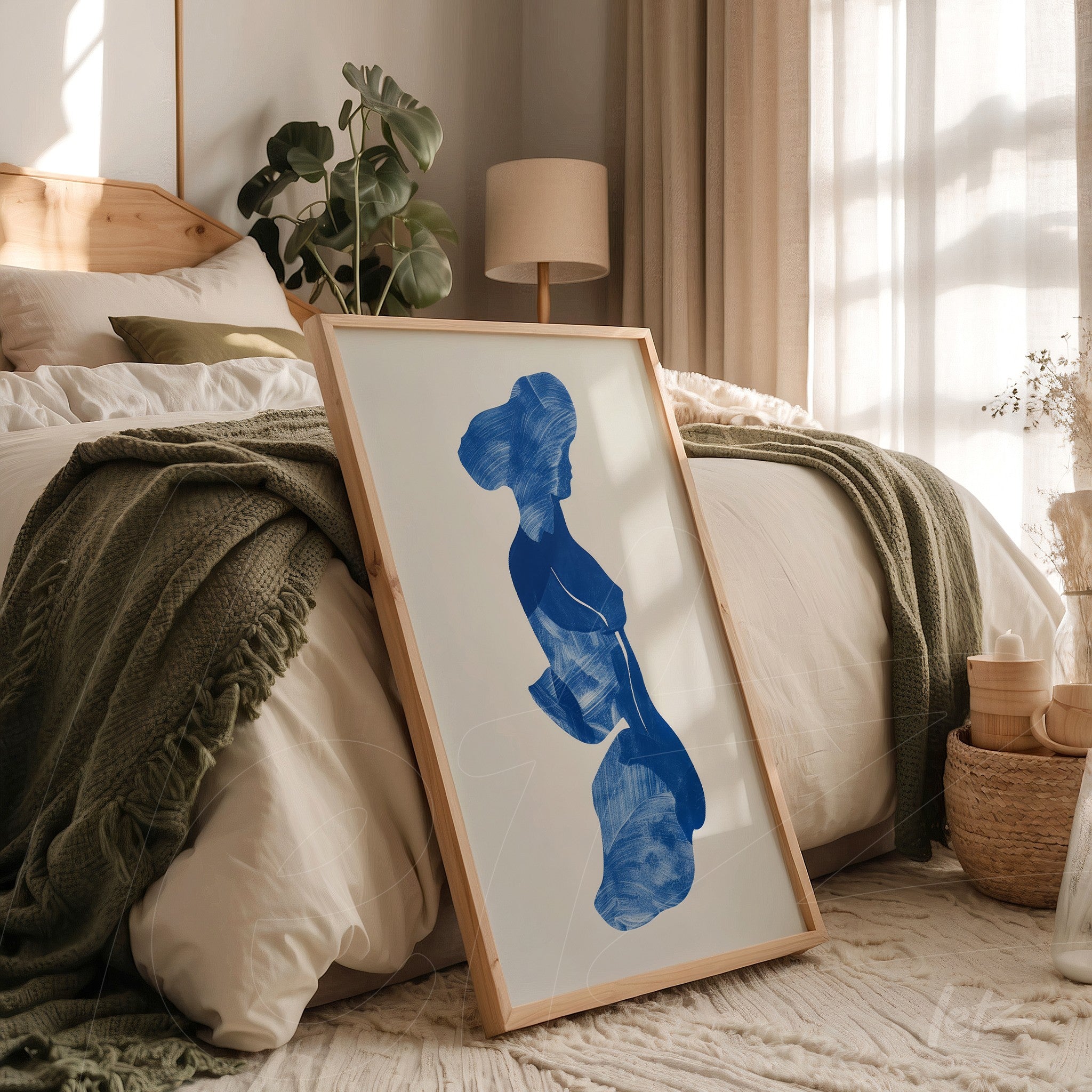 abstract wall art in blue featuring a female figure in a light wood frame leaning against a bed with neutral bedding