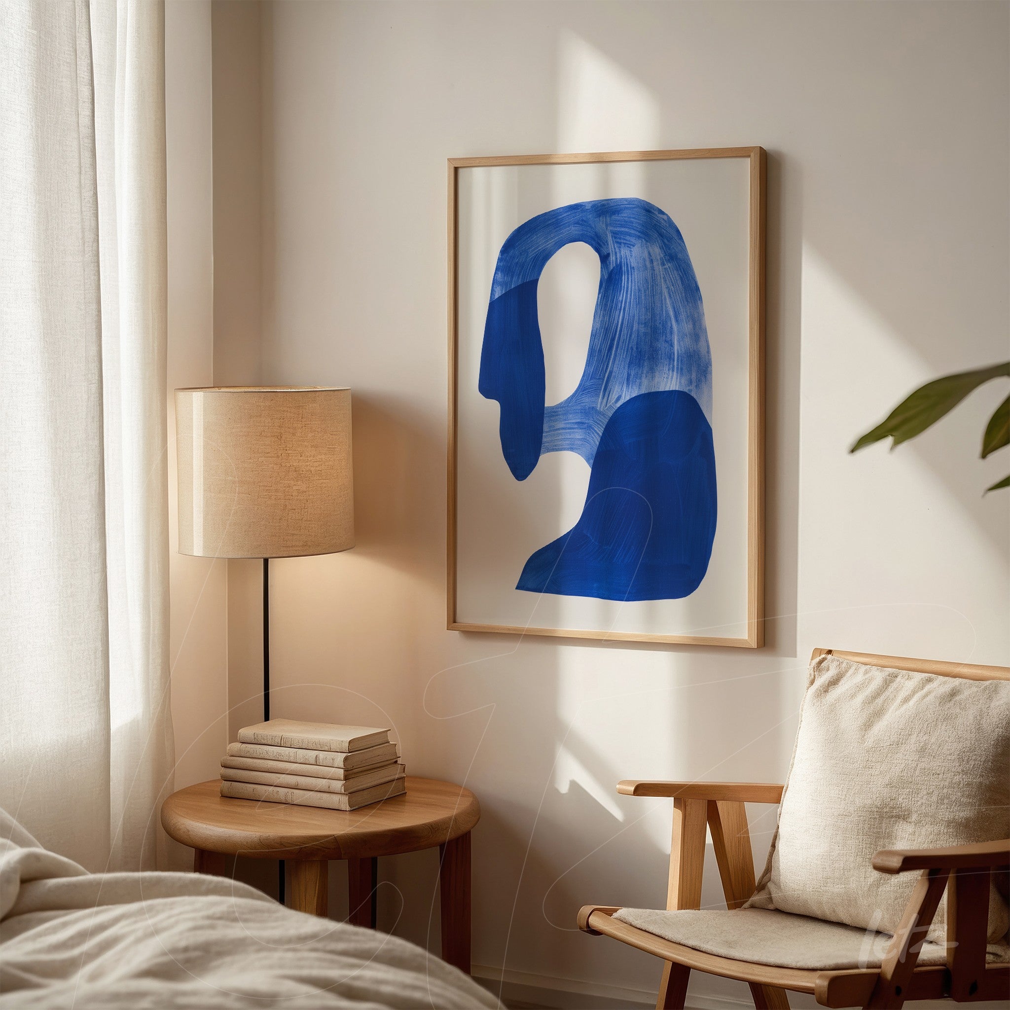 framed abstract wall art in blue with light frame, set against a neutral background featuring decor elements like a lamp and books beside it