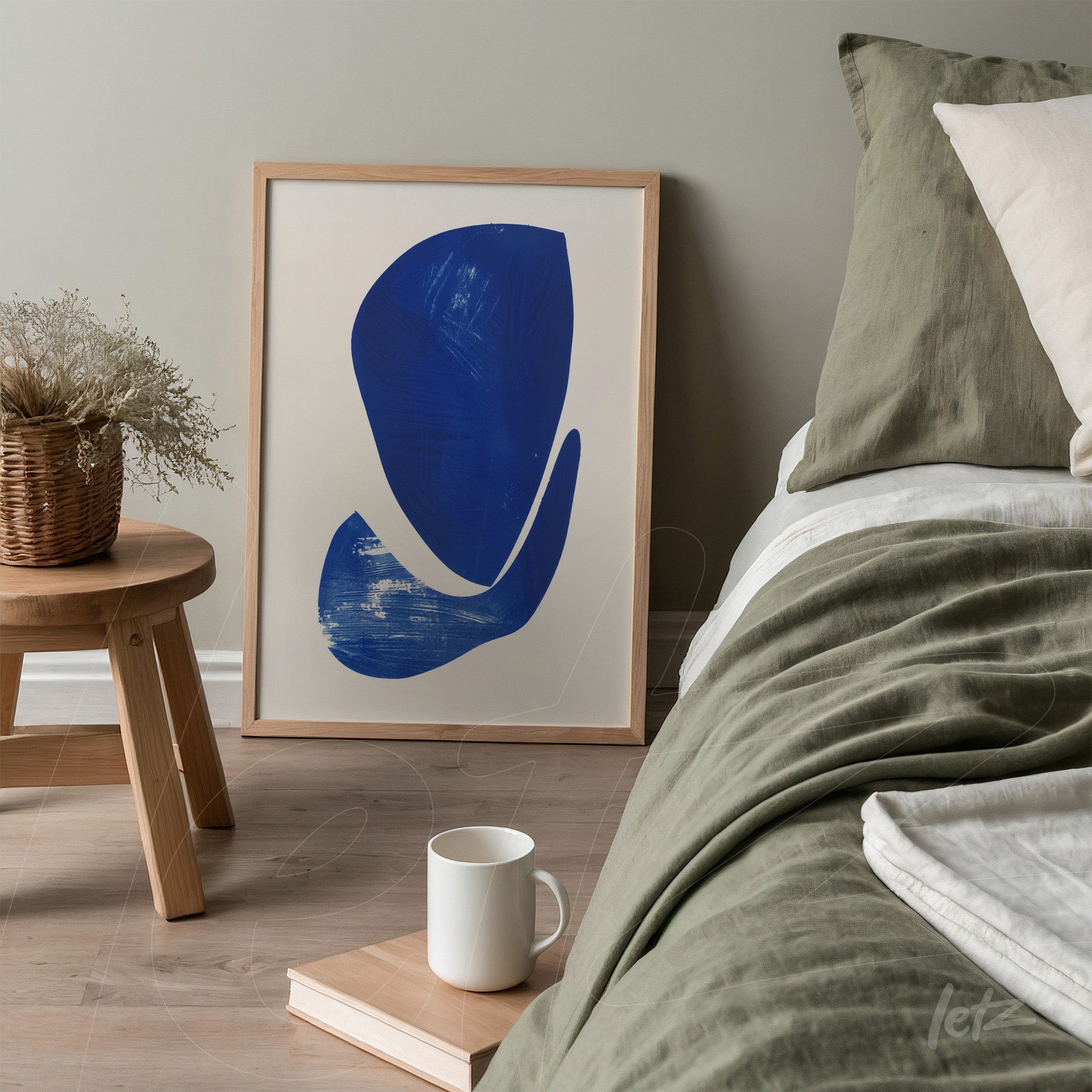 framed wall art featuring abstract design in blue, positioned next to a bed with green and beige bedding