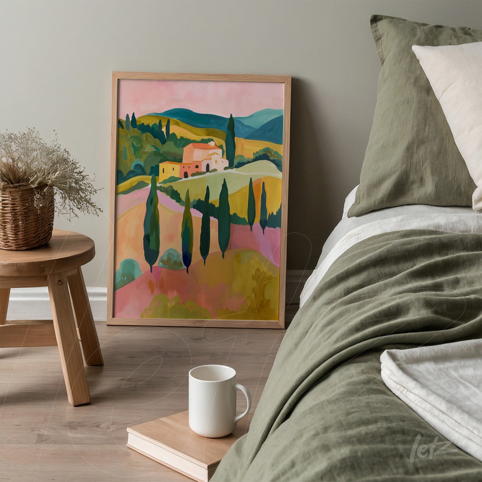 framed wall art featuring a vibrant rural landscape in shades of pink, green, and yellow, leaning beside a bed with neutral bedding