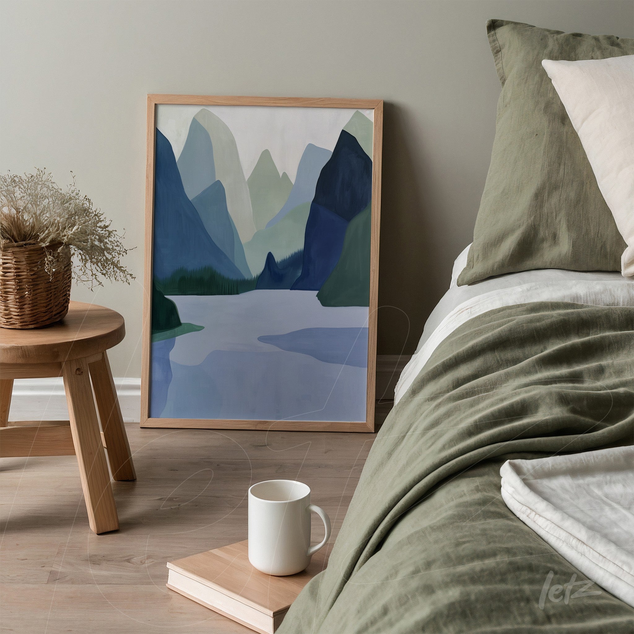 framed artwork of mountain landscape in shades of blue and green leaning beside a bed in a neutral-colored room