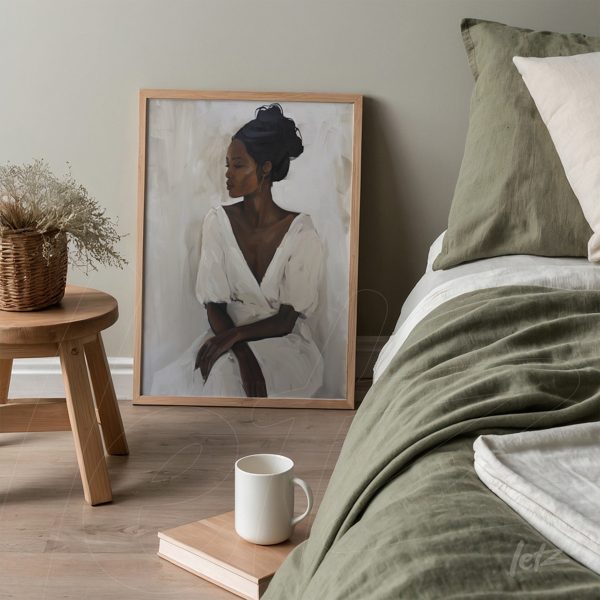 framed portrait of a dark-skinned woman in a white dress with a light wooden frame leaning next to a bed with green bedding and light pillows