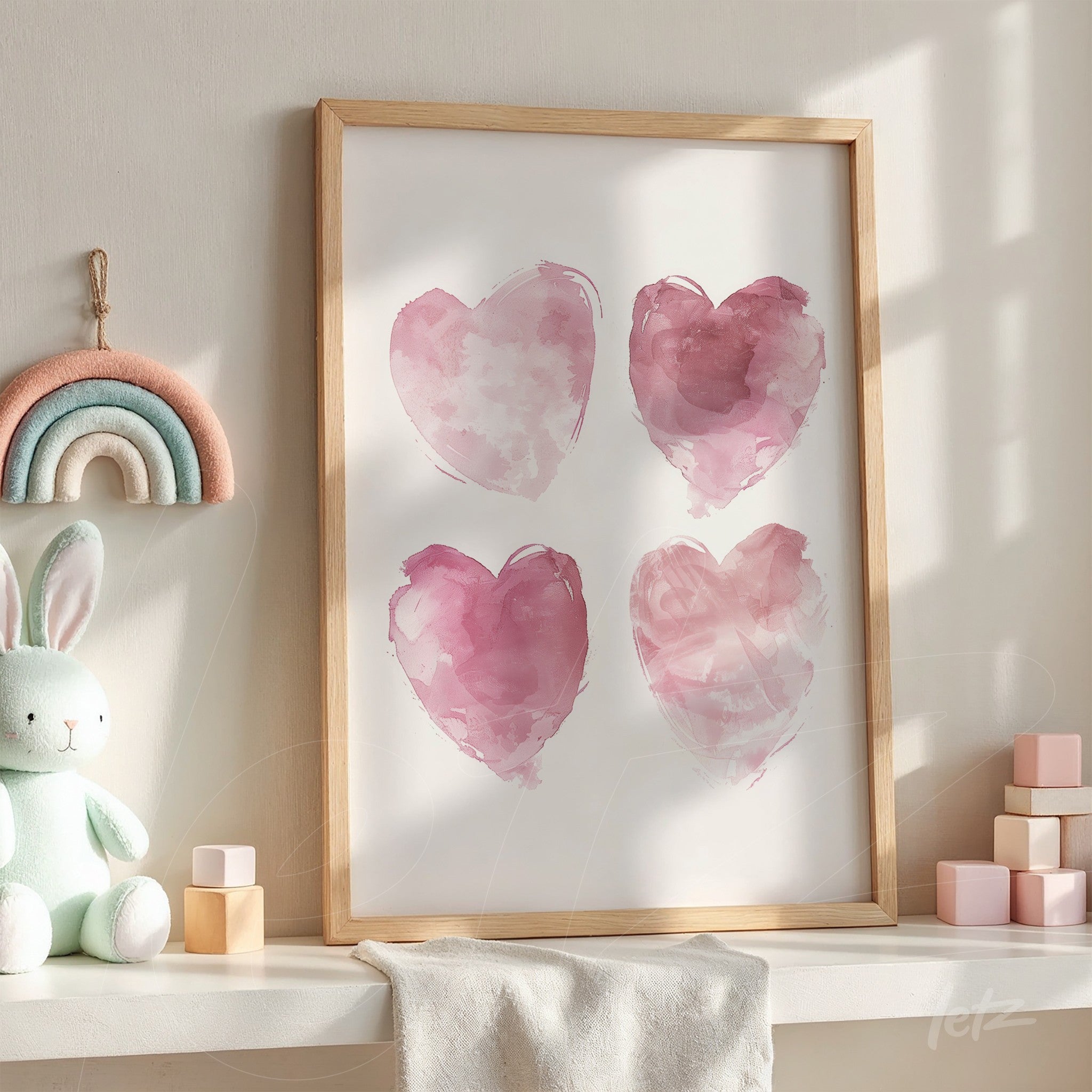 framed art print featuring four watercolor pink hearts in a light wood frame displayed in a brightly lit setting