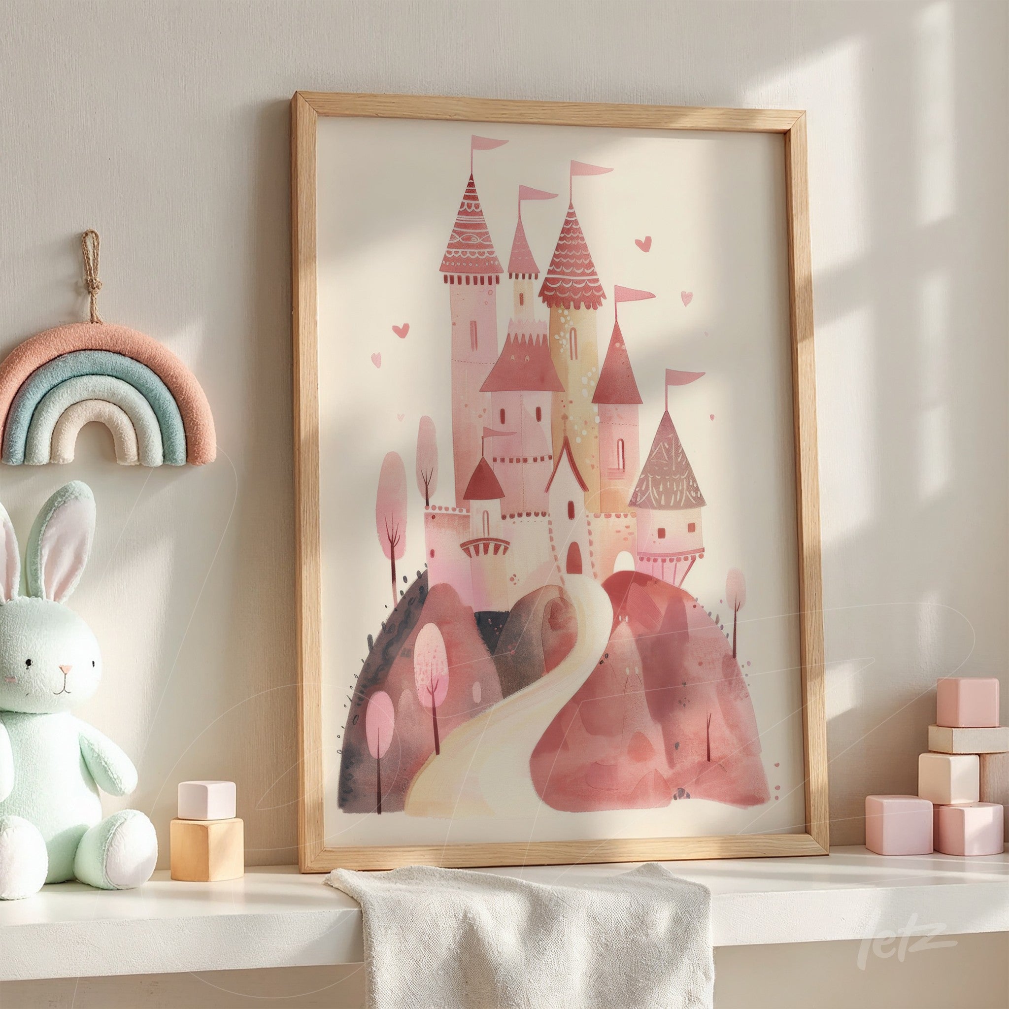 framed illustration of a pink watercolor castle displayed on a shelf with children's toys and a felt rainbow decor