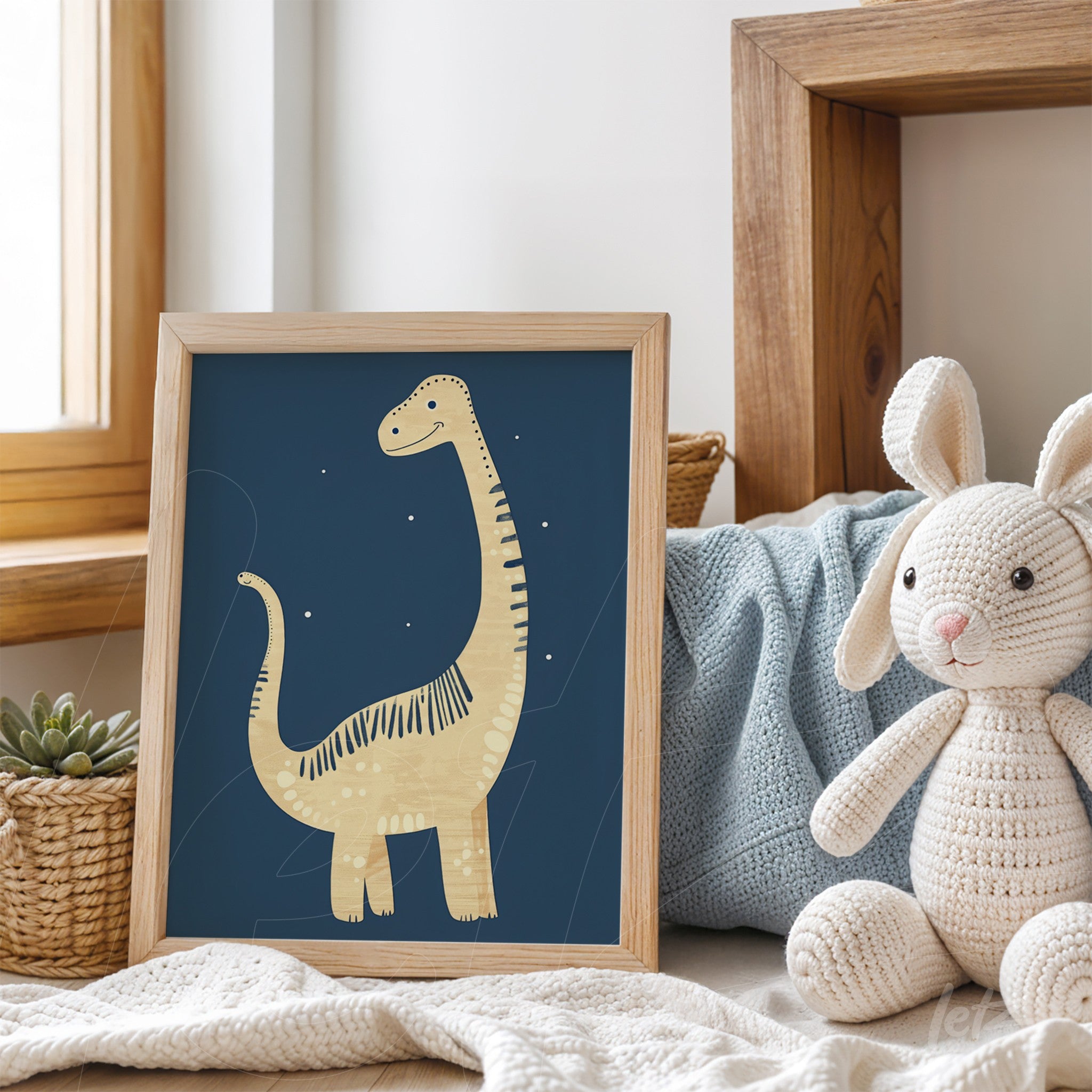 framed wall art featuring a dinosaur illustration with a light wood frame on a table alongside a plush rabbit toy