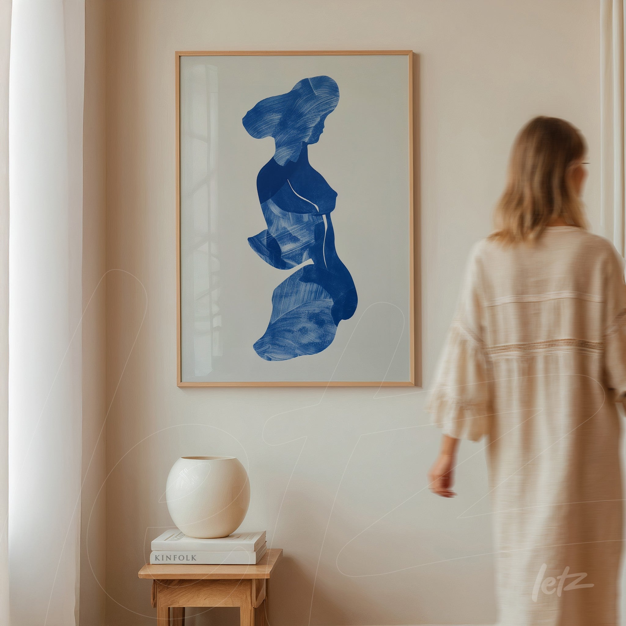 framed artwork featuring an abstract blue silhouette of a woman against a light neutral wall