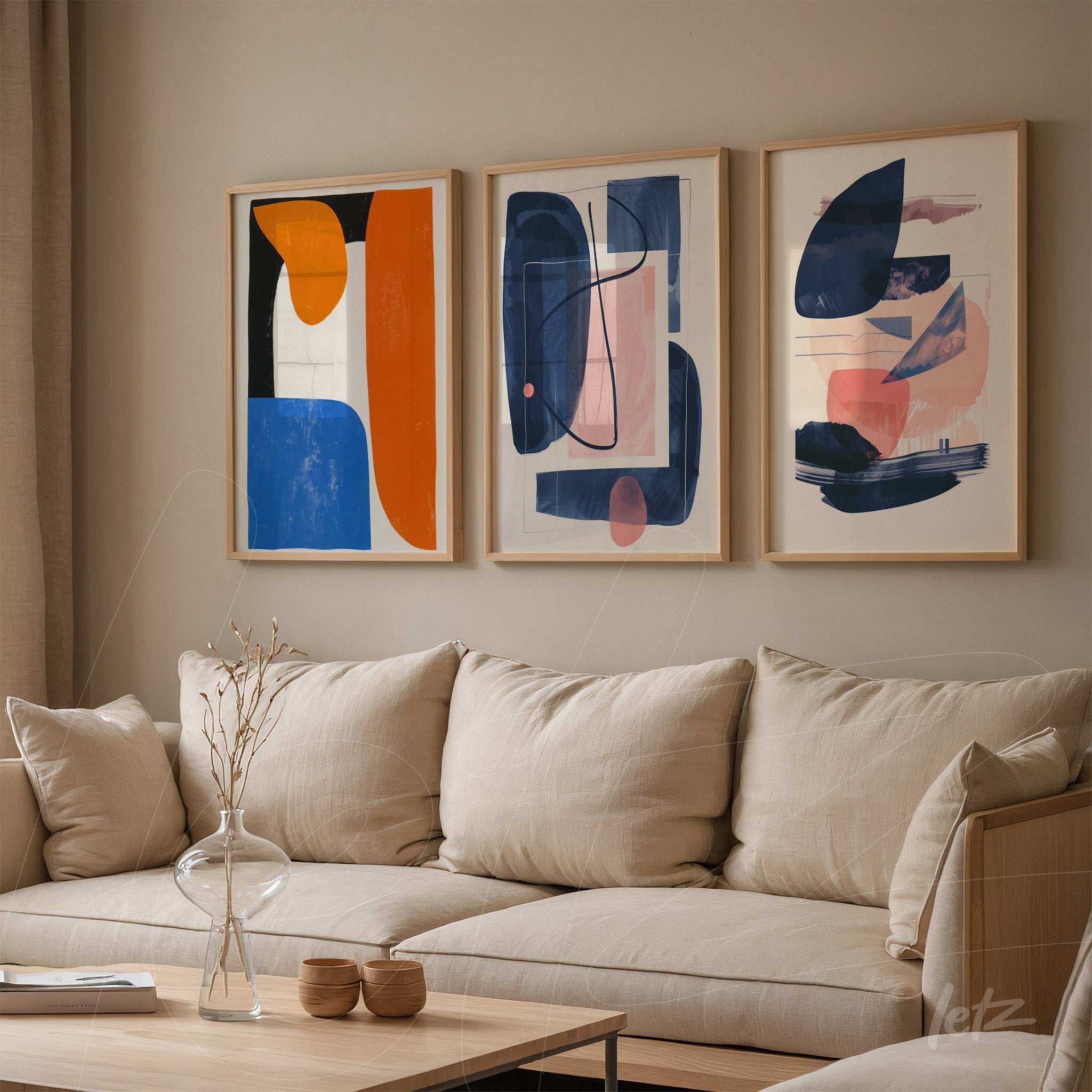 composition of three abstract framed artworks in light wood above beige fabric sofa