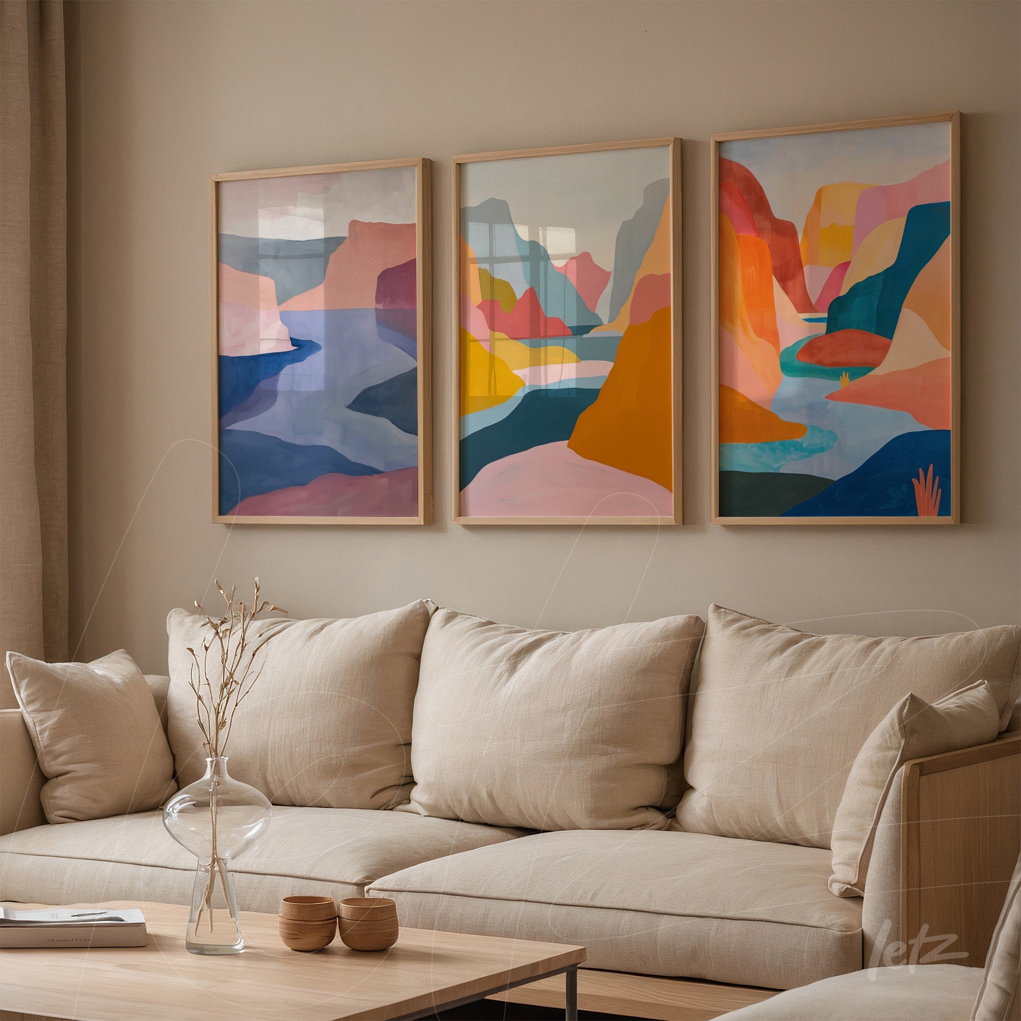 collection of framed artwork featuring abstract landscapes in warm and cool tones displayed above a neutral sofa