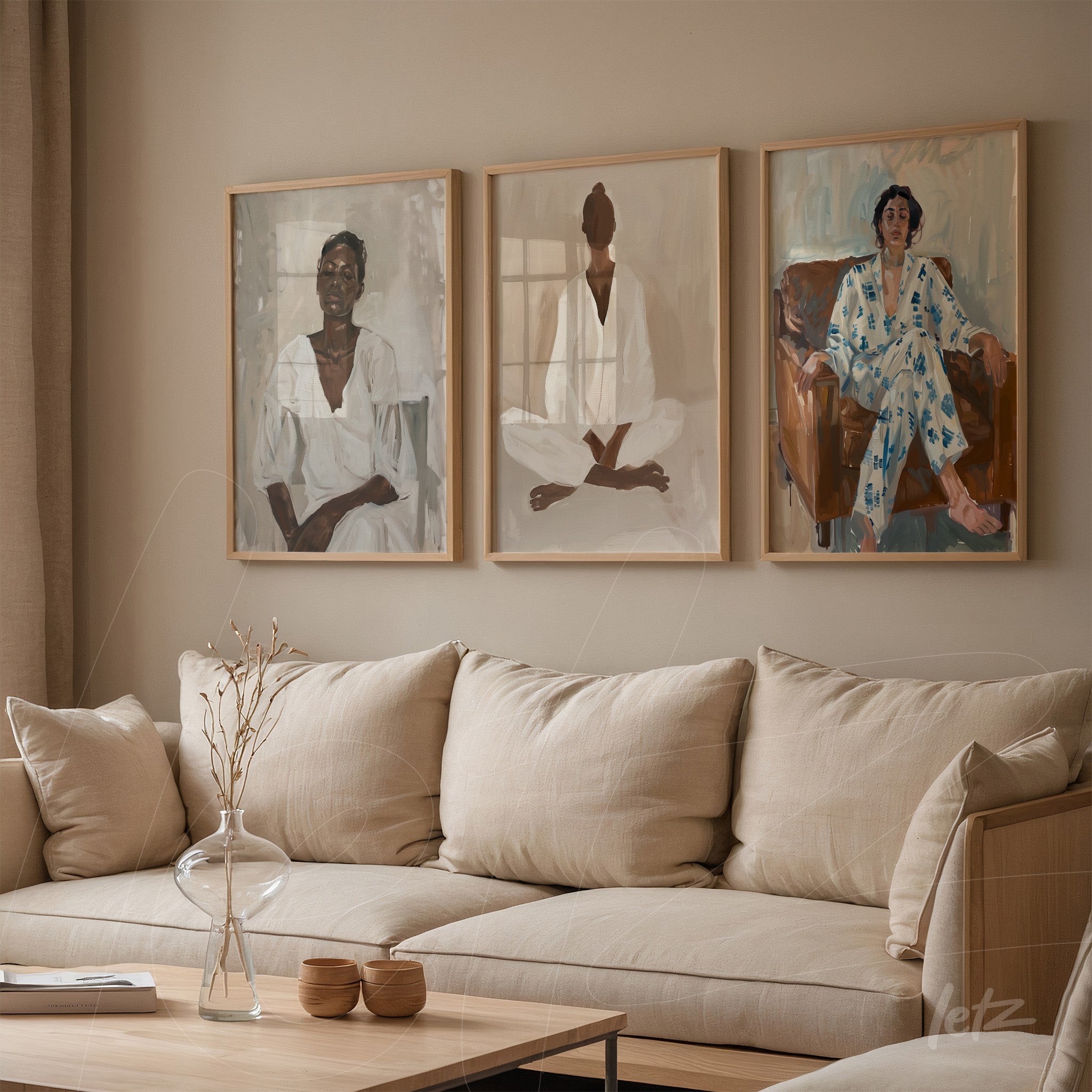 three framed portraits of female and male figures in light frames arranged on a beige wall beside a sofa with neutral cushions