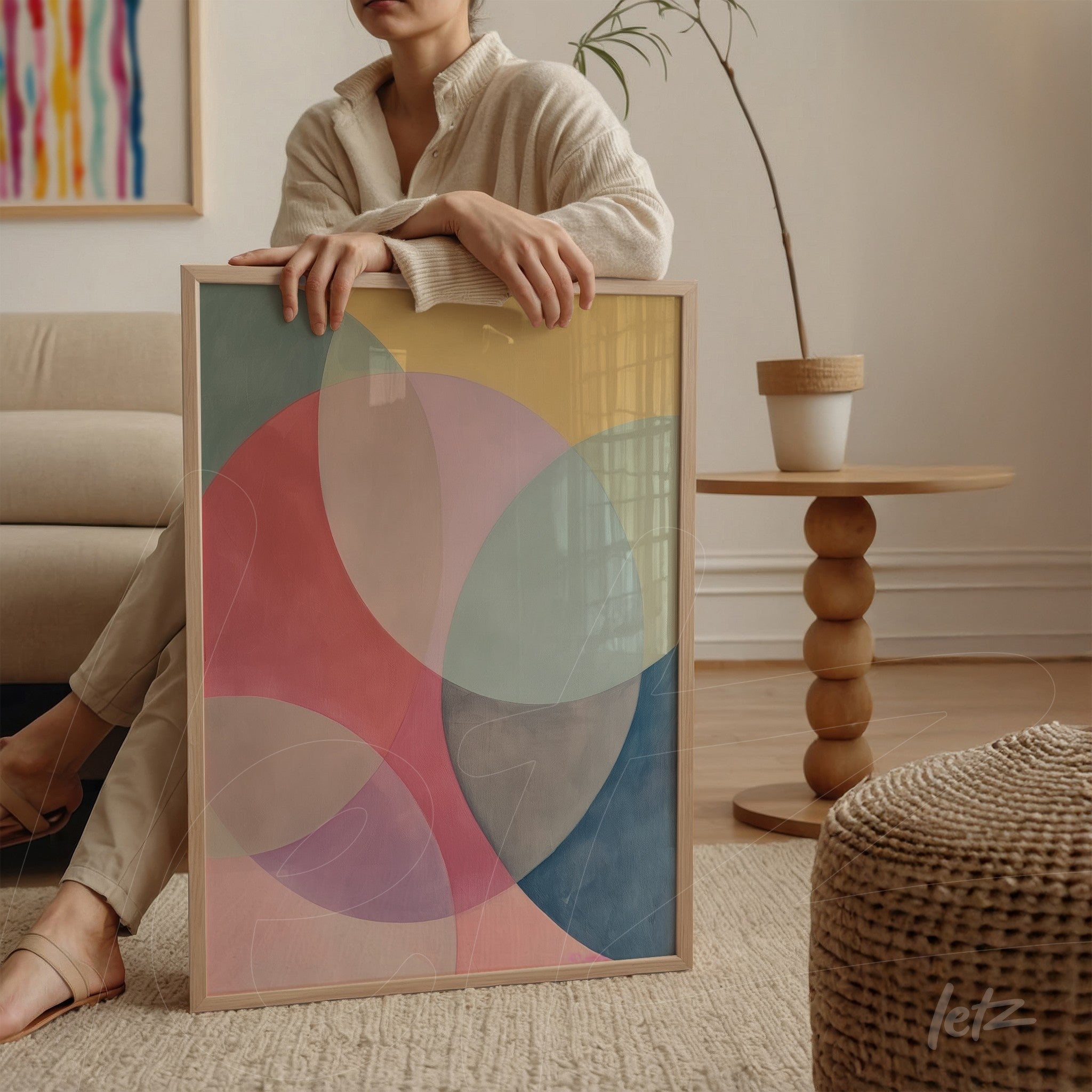 framed abstract art in soft colors displayed in a minimalist setting with light wood frame