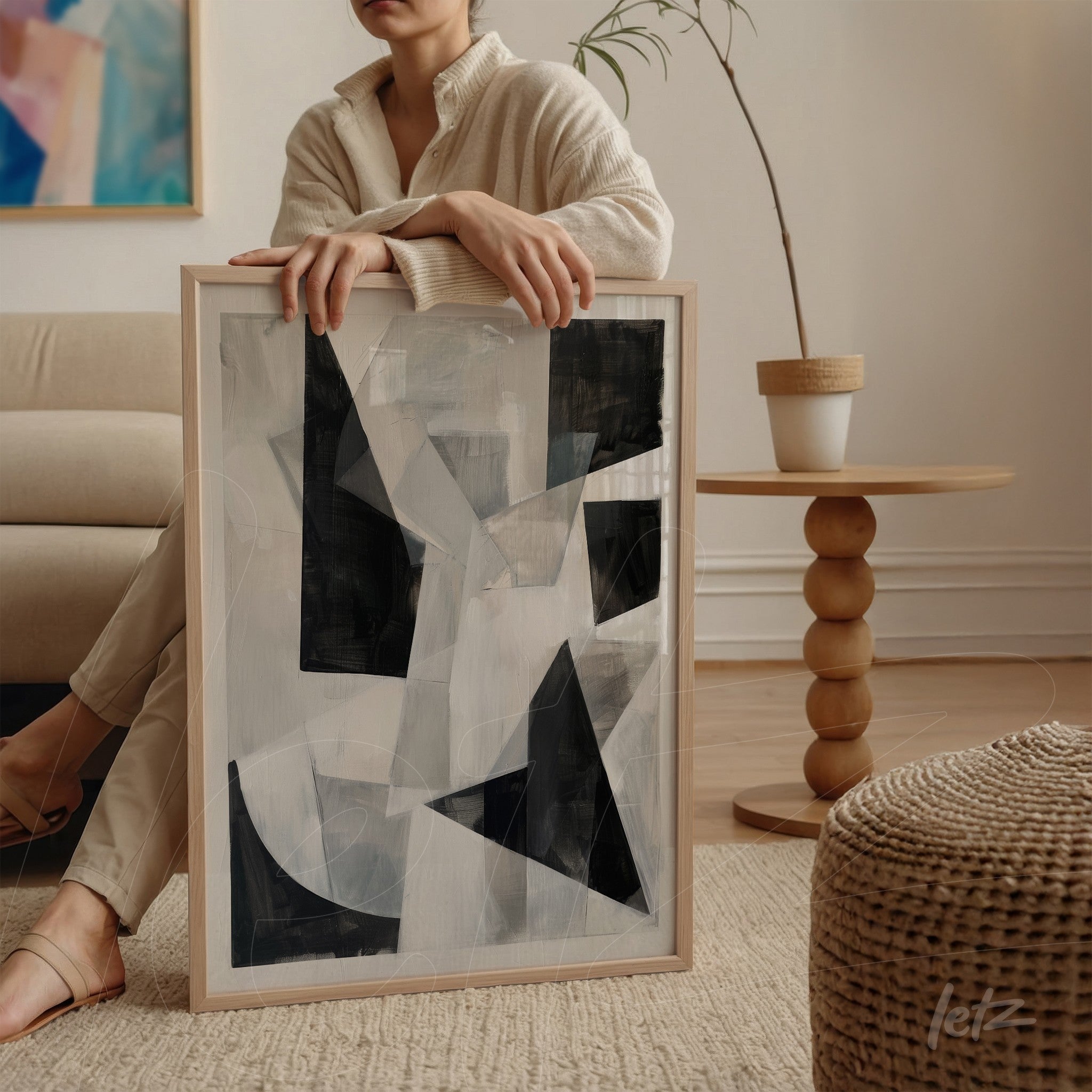 framed abstract wall art in black and white showcased by a woman sitting in a modern living room