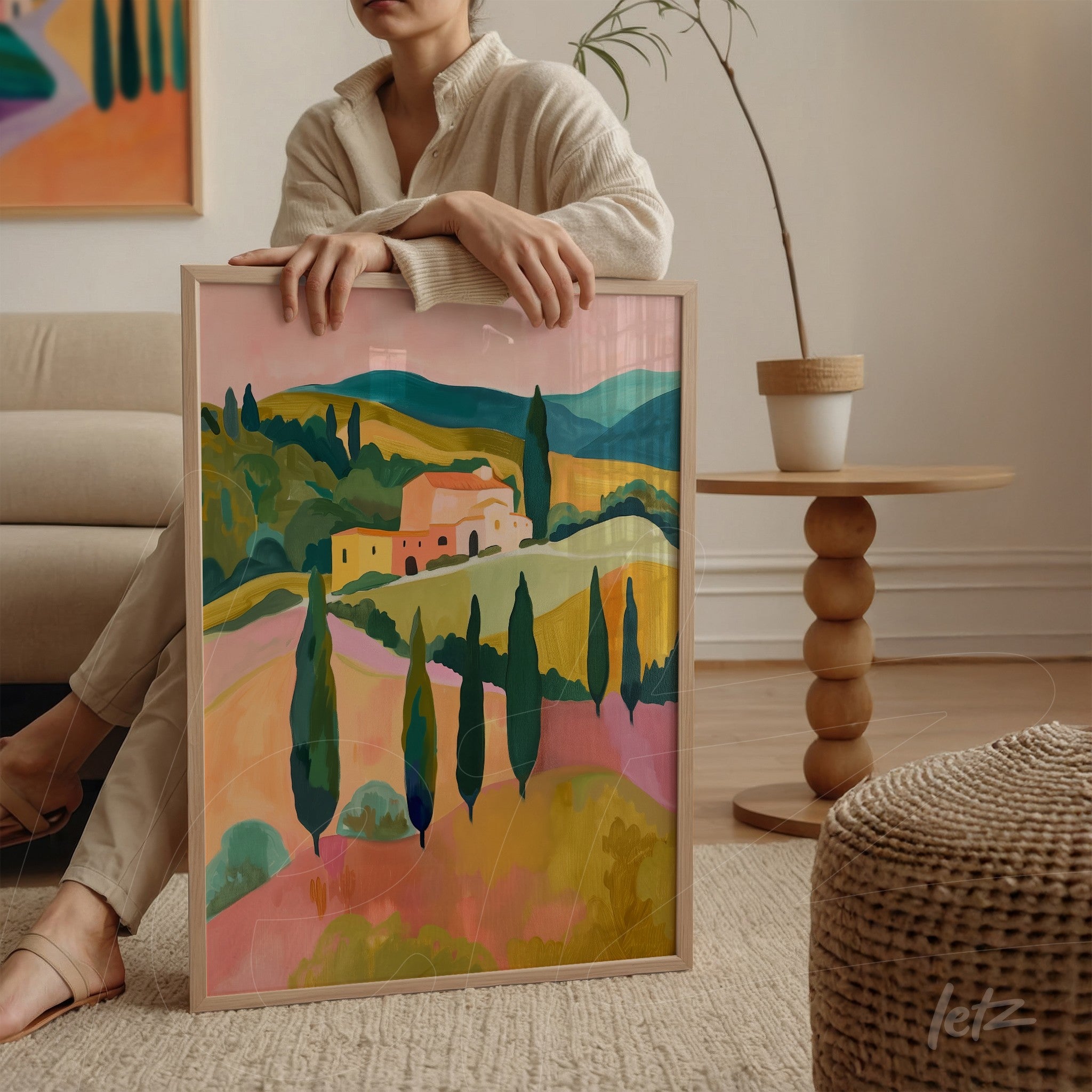 framed wall art depicting a vibrant countryside landscape with rolling hills and cypress trees displayed in a cozy living space with a sofa and wooden side table