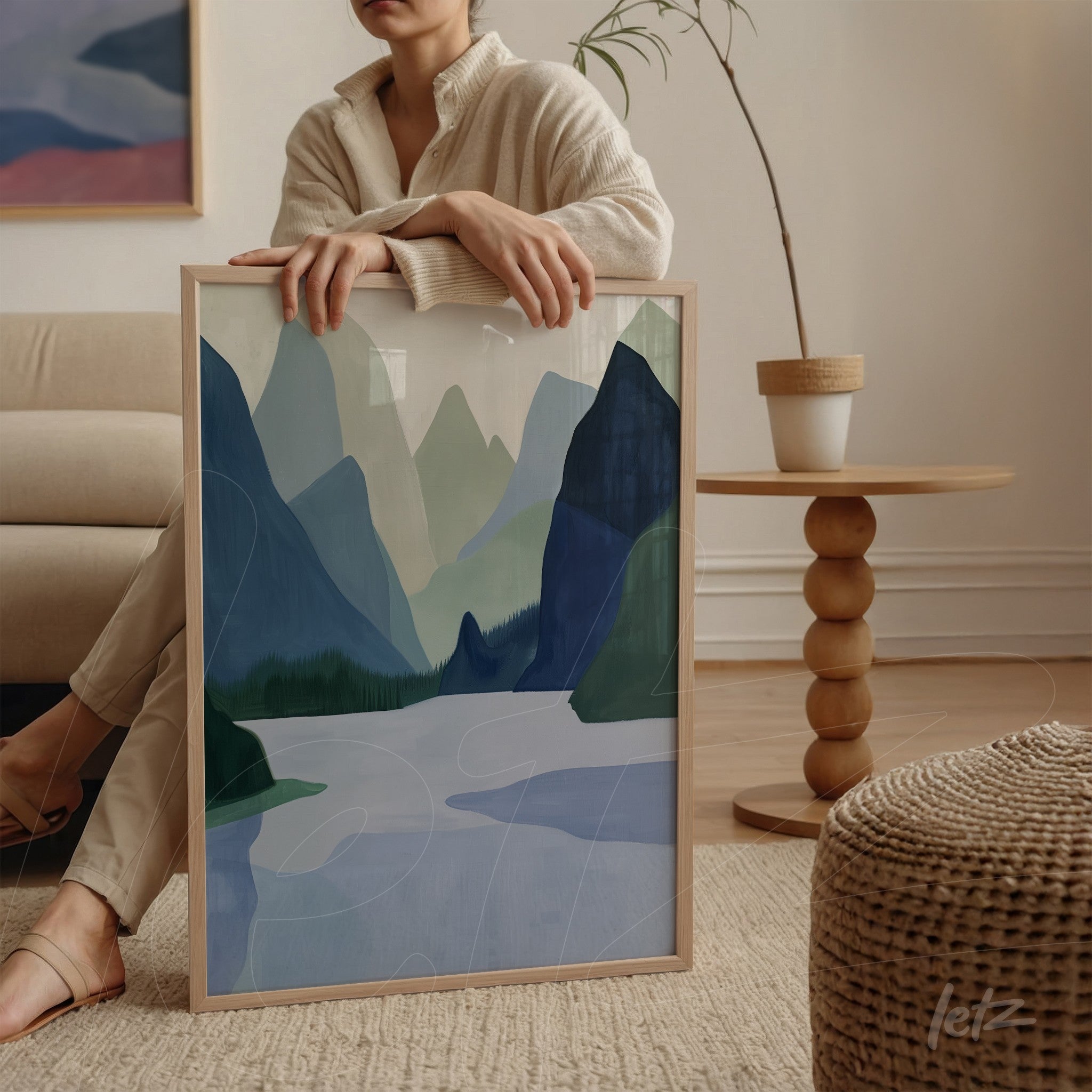 framed abstract artwork of green mountains and a lake with light wood frame