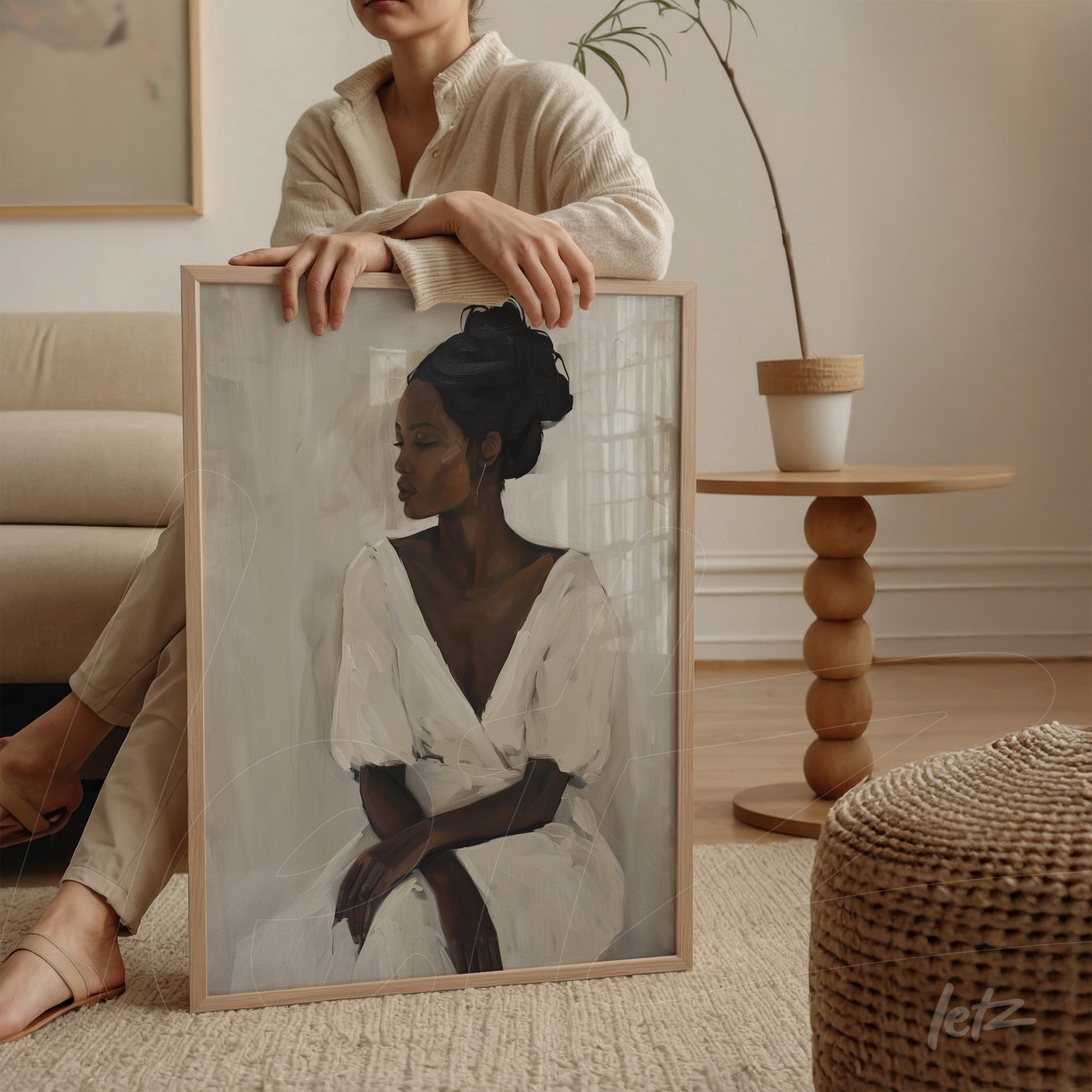 framed abstract portrait of a woman in a white dress resting on a chair beside a light wood table