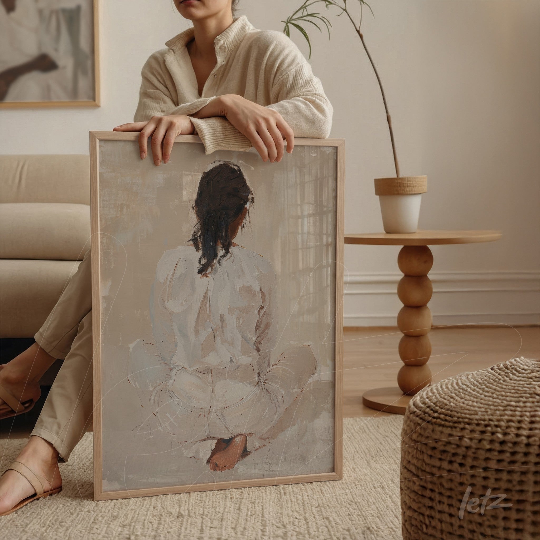 framed artwork of a seated figure from behind in light frame displayed beside round table