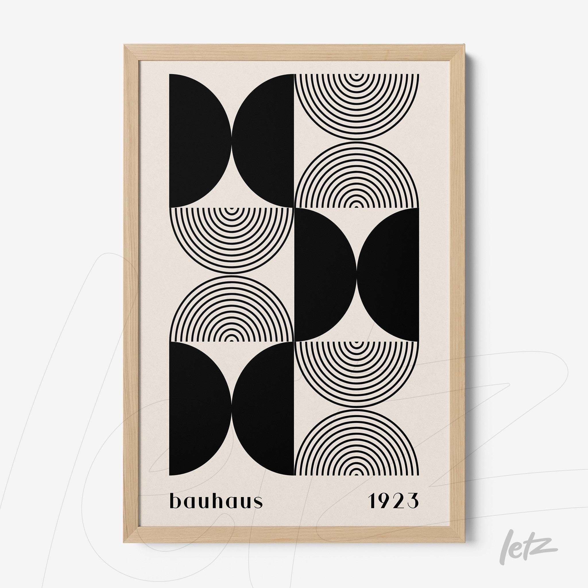 poster print of Bauhaus art with black geometric shapes and concentric circles in light wood frame