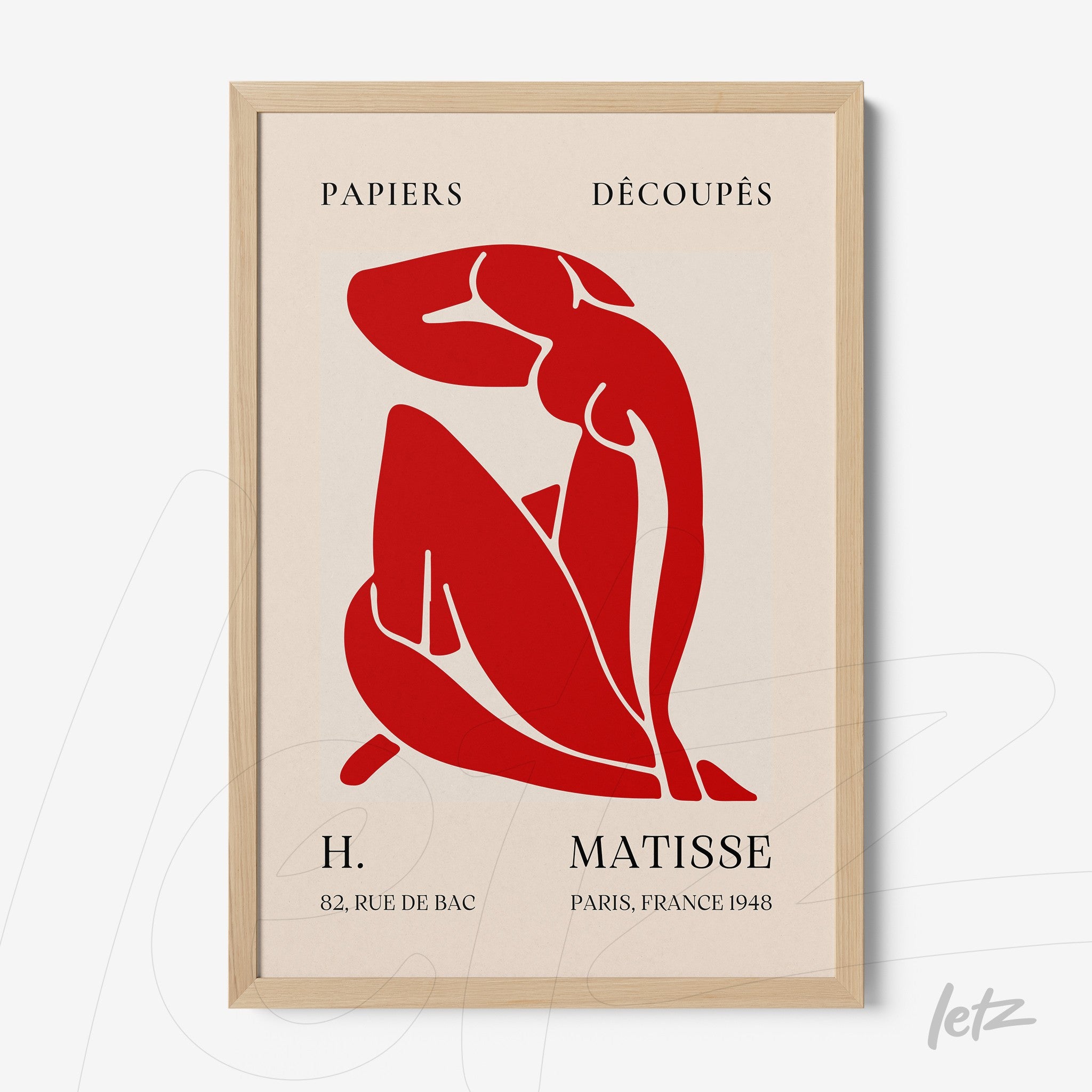 framed wall art featuring a red cut-out of a female figure on beige background with light wood frame