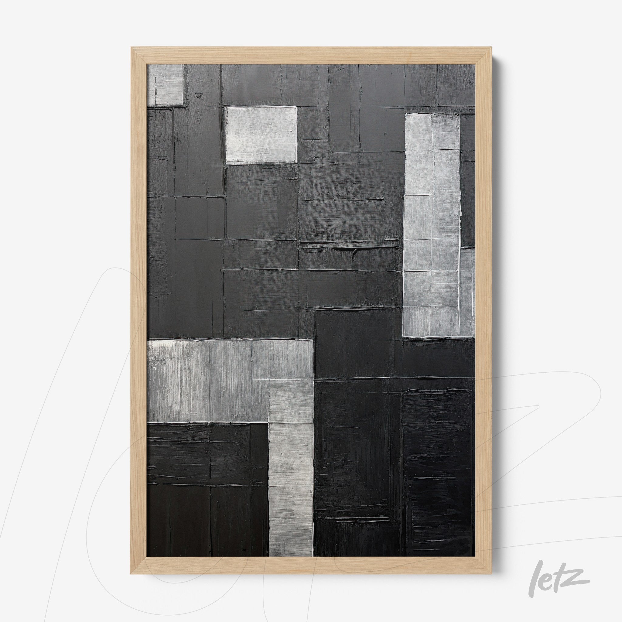 abstract wall art in shades of black and gray with varied textures, framed in light wood
