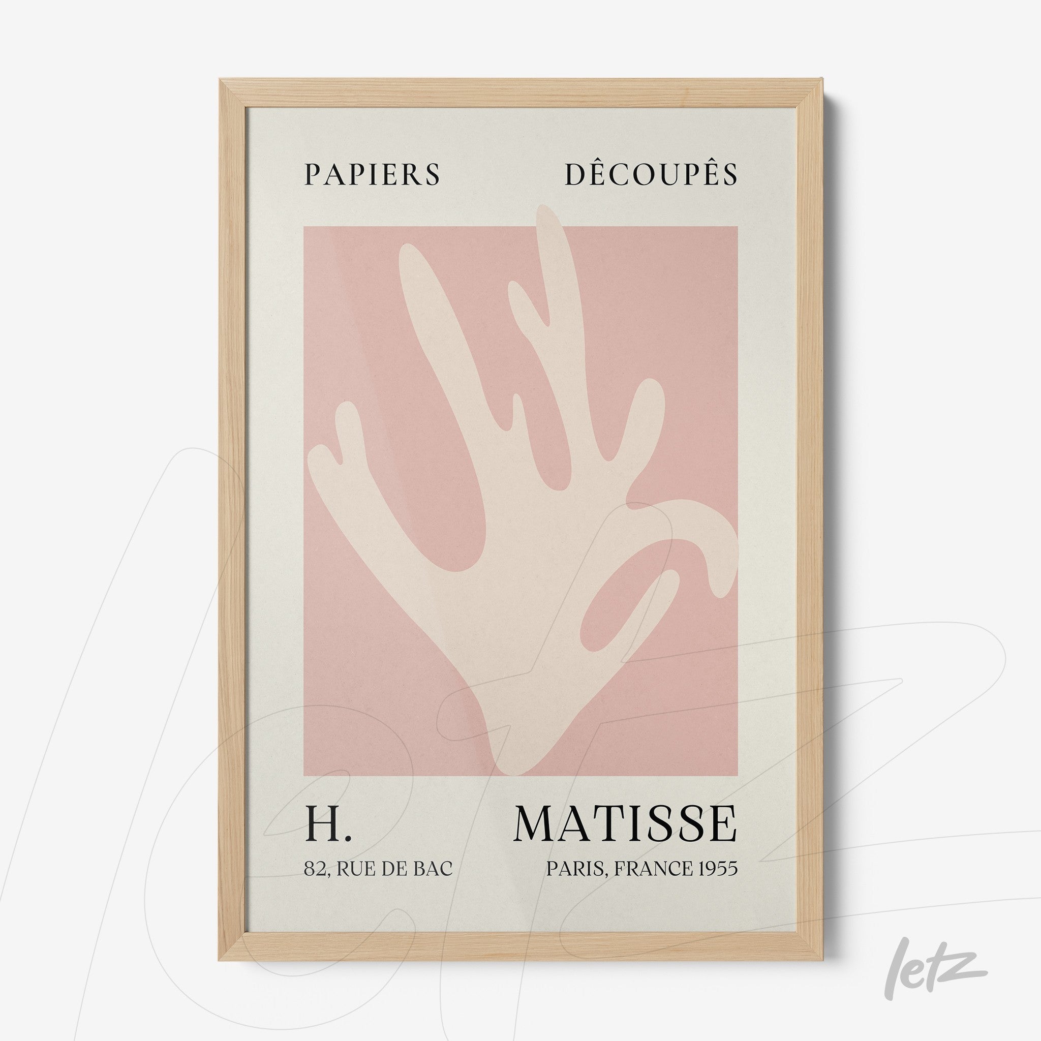 framed abstract art of a hand in pink background with light wood frame