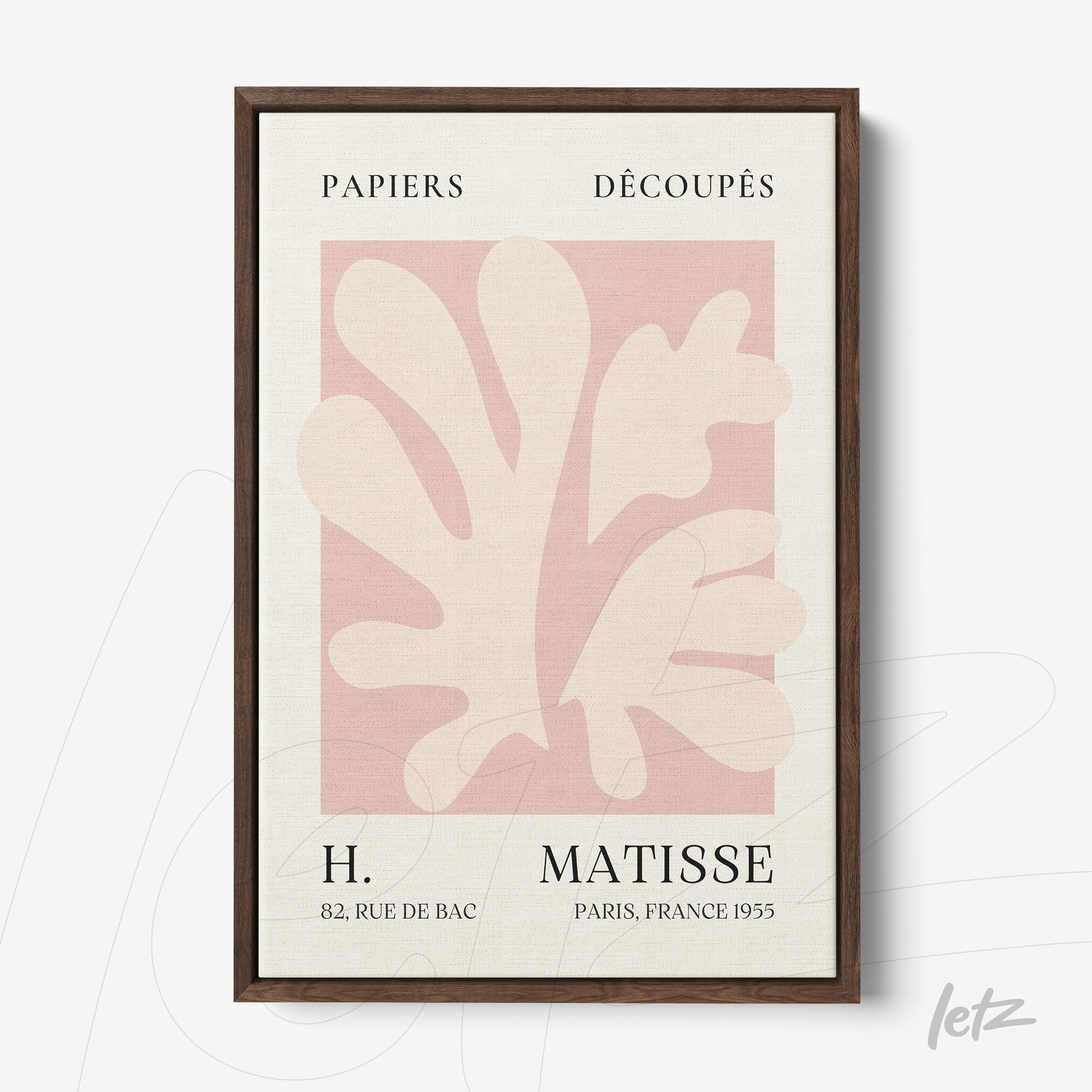 framed wall art featuring paper cutouts in shades of pink and cream with dark wood frame