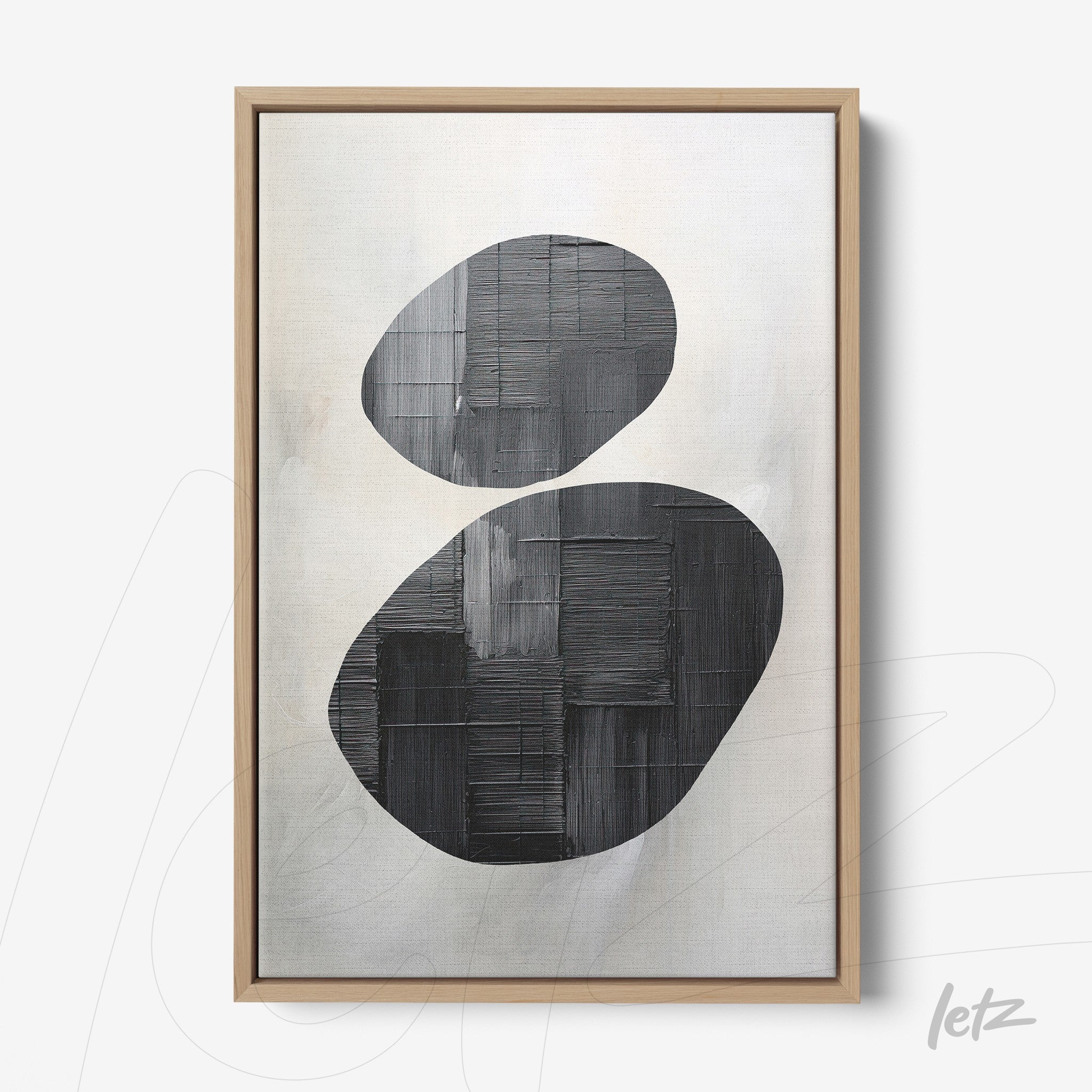 abstract wall art featuring black oval shapes on a light background framed in light wood