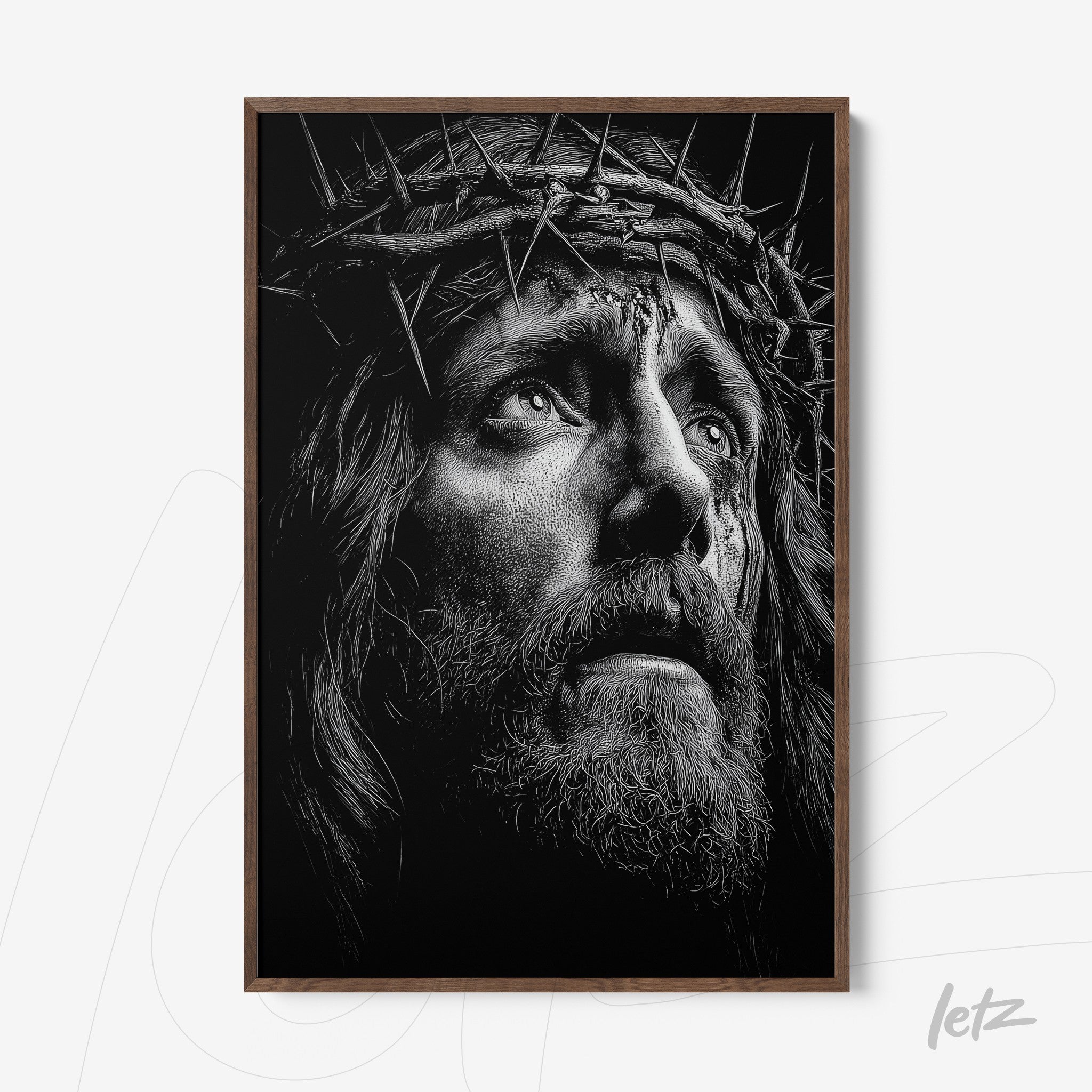 framed wall art in black and white depicting a male face with a crown of thorns in a light wood frame